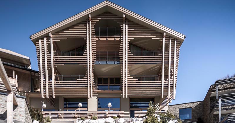 An Exterior Of Horizontal Wood Poles Creates A Unique Facade For This Hotel