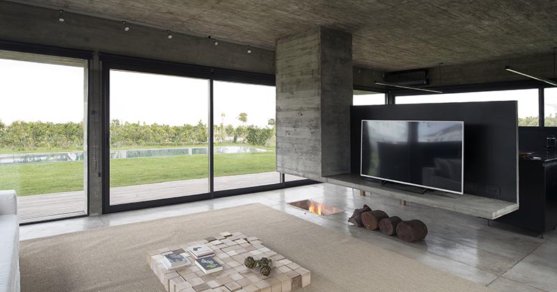 A Concrete Divider Hangs Above An In-Floor Fireplace Inside This Home