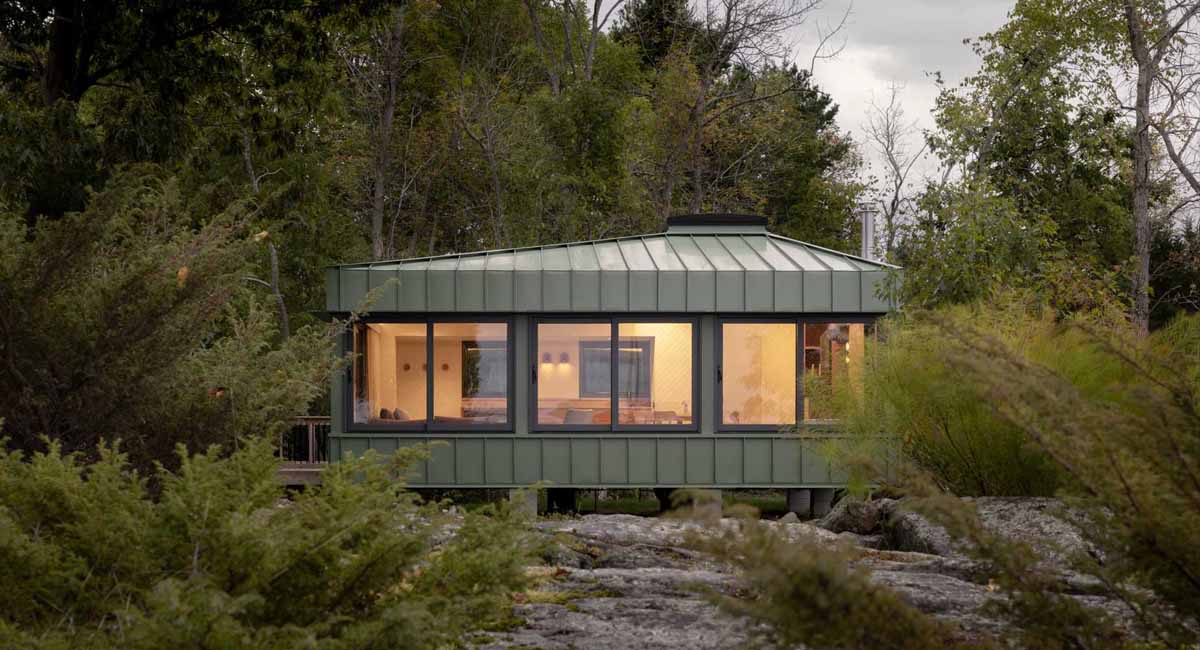 Green Metal Siding Allows This Small Cottage To Blend In With Its Surroundings