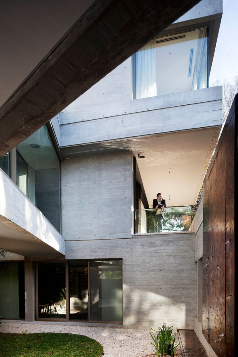 A Concrete House With A Pond And A Green Roof Incorporated Into Its Design