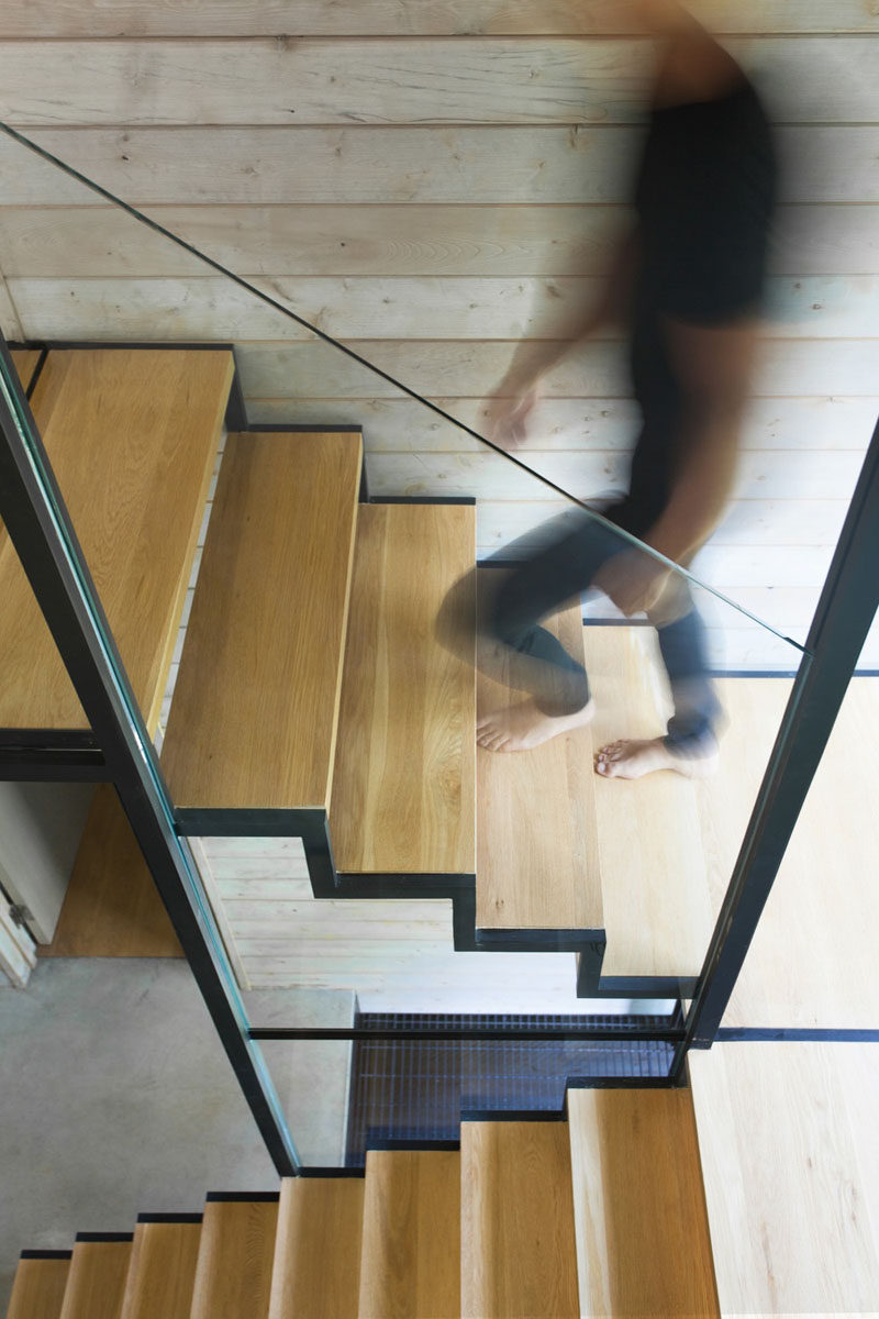 Wood and steel stairs with a glass handrail lead to the second floor of this modern vacation house. #ModernStairs #StairDesign #WoodAndSteel