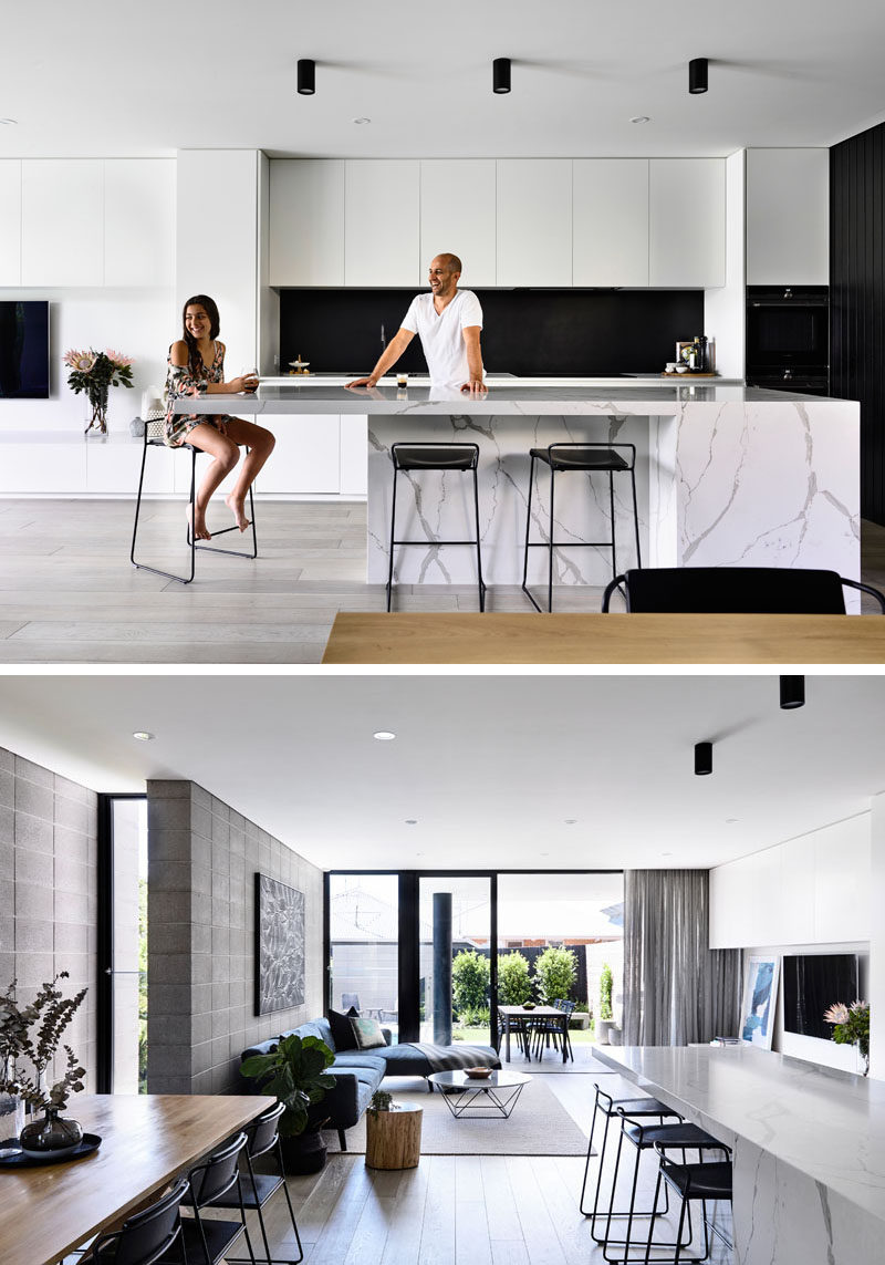 In this kitchen, a black backsplash ties in with the black timber, while minimalist, hardware free white cabinets and a stone island with seating complete the modern look. #ModernKitchen #BlackAndWhiteKitchen