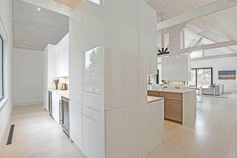 This modern kitchen features a pantry behind it that has views of the garden. #ModernPantry #WhiteCabinets #KitchenDesign