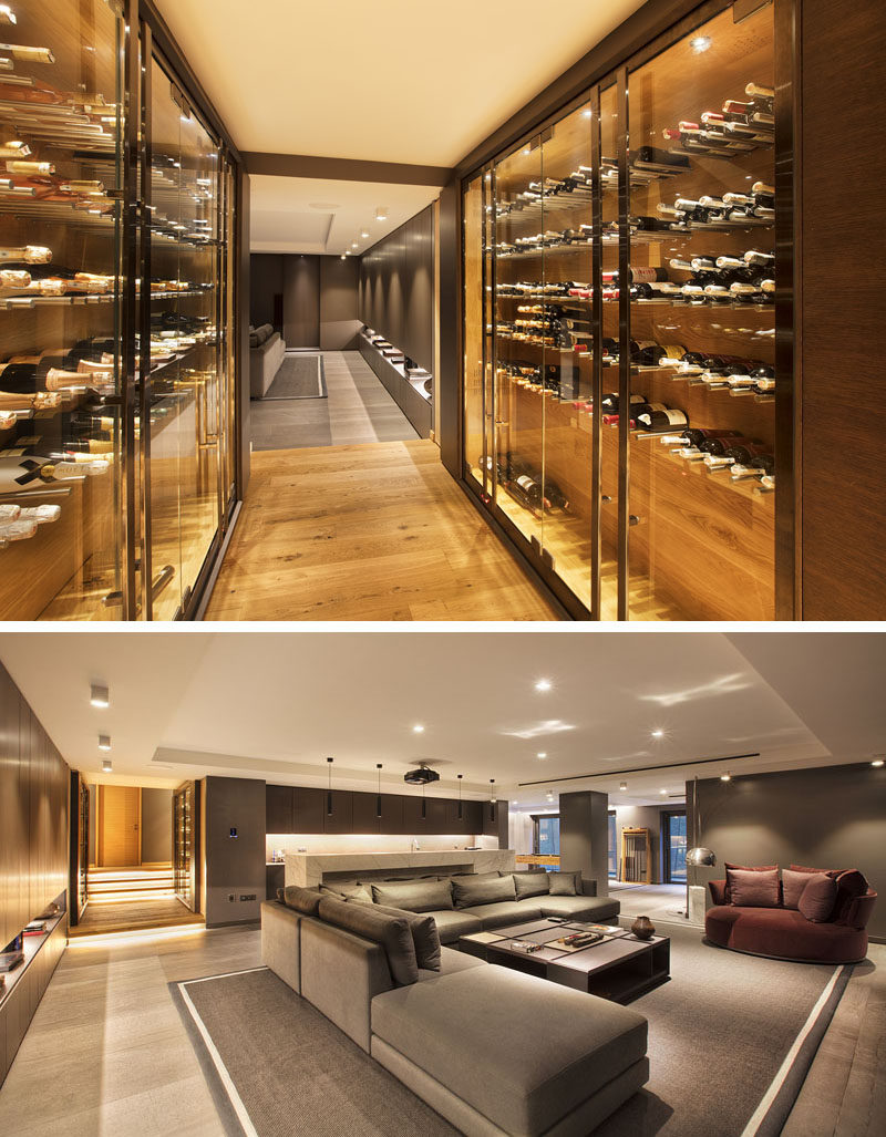 This modern hallway with built-in wine storage, opens up to a family room furnished with a large couch, a bar, and a games area. #WineStorage #FamilyRoom #InteriorDesign