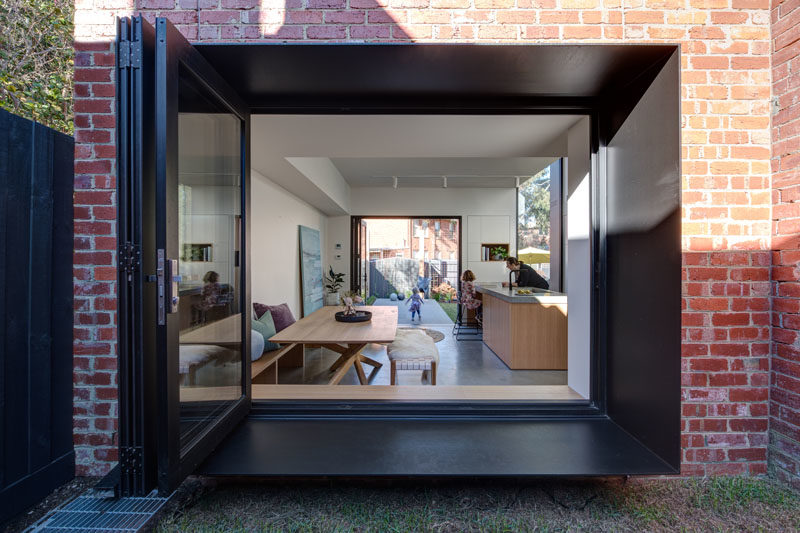 Window Ideas - A large window with a deep steel frame opens up to a small grassy courtyard. #WindowIdeas #WindowDesign