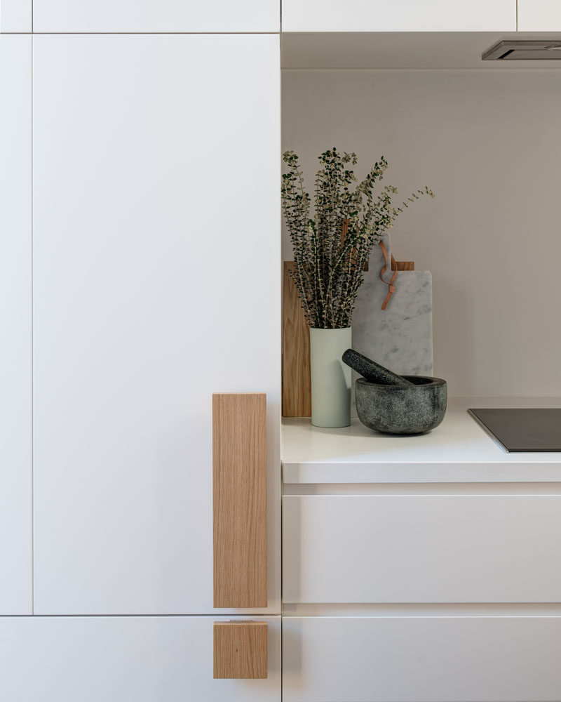 Kitchen Ideas - Oversized wood handles add a touch of nature to these minimalist white cabinets. #KitchenHandles #KitchenHardware #CabinetHardware