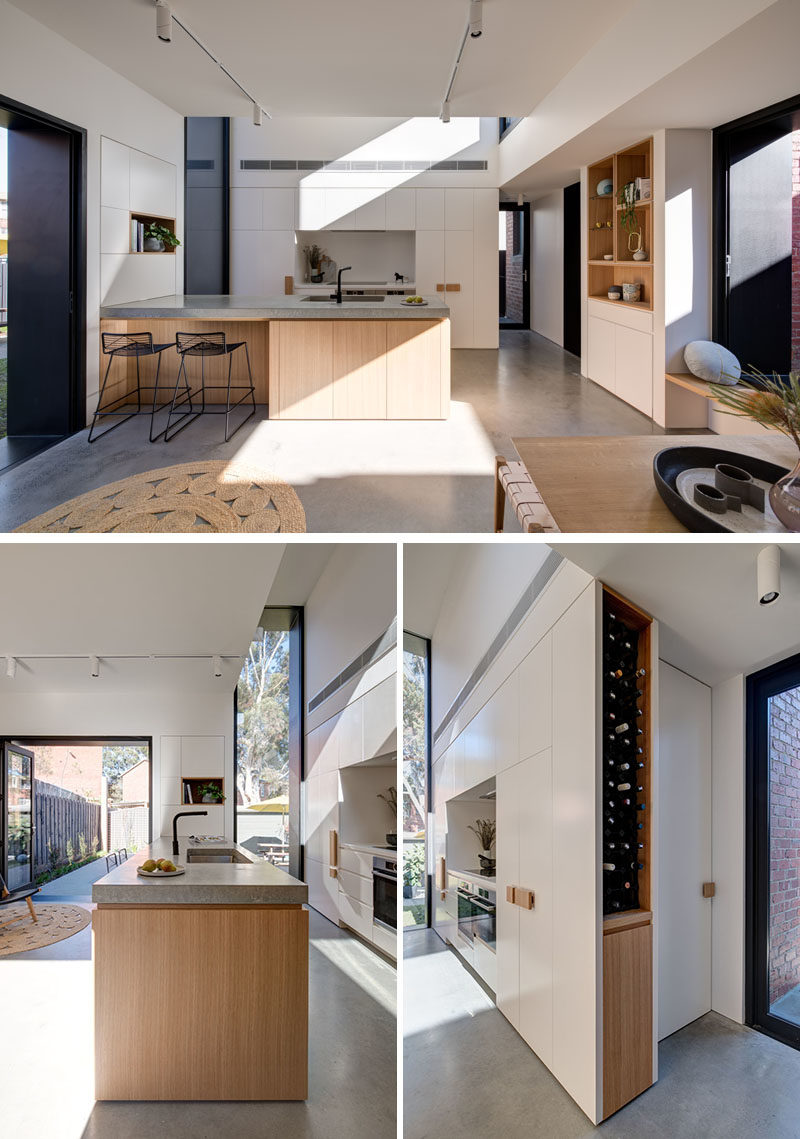 Kitchen Ideas - This modern kitchen has a large wood peninsula, minimalist white cabinets, and built-in wine storage. Behind the kitchen is a door that leads to the laundry room. #KitchenIdeas #ModernKitchen #KitchenDesign