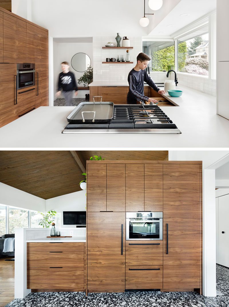 This remodeled kitchen has a bright and modern appearance with a large peninsula, wood cabinets, and a dining area with banquette seating. #ModernKitchen #WhiteKitchen #WoodKithen #KitchenDesign