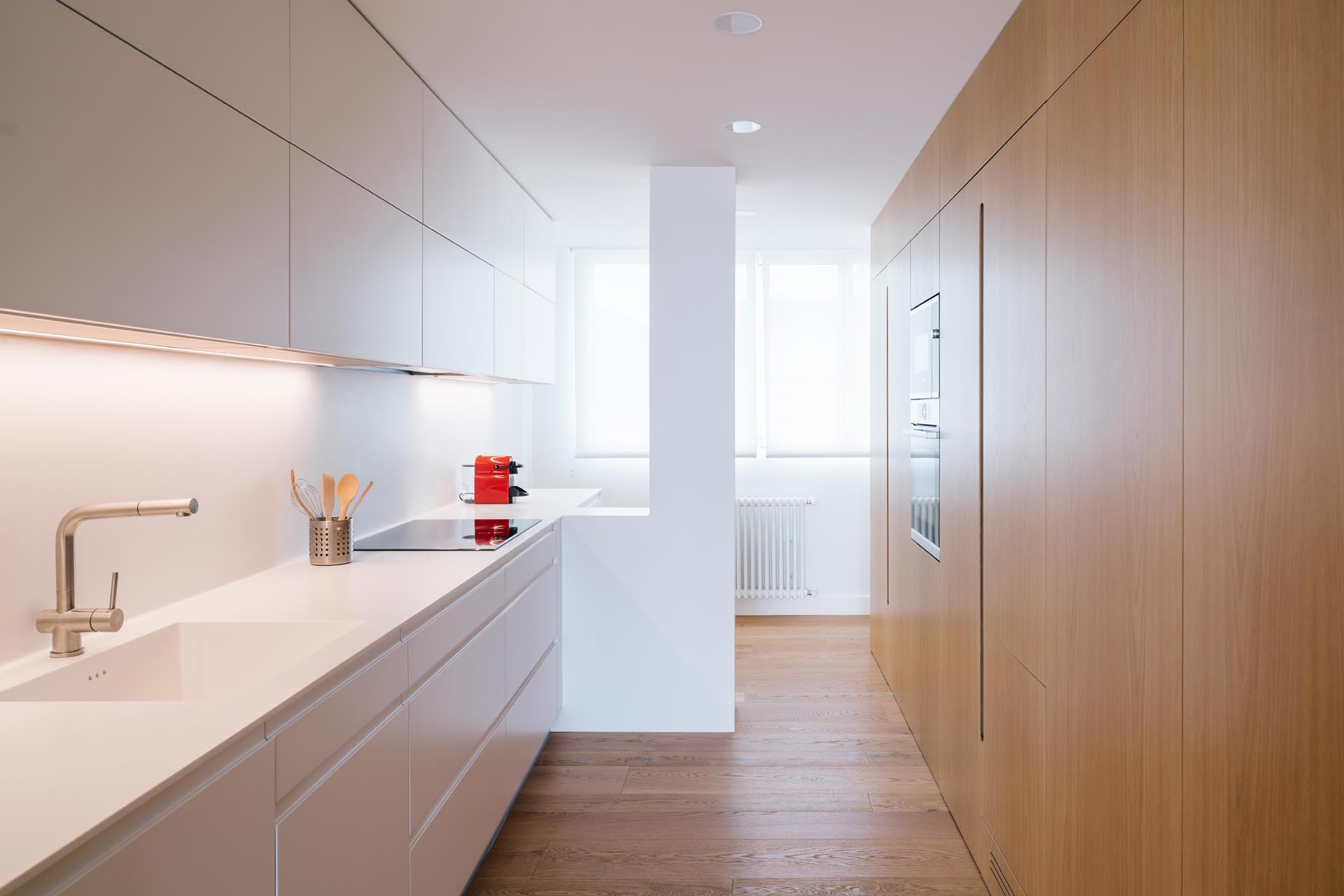 A modern kitchen with minimalist white and wood cabinets.