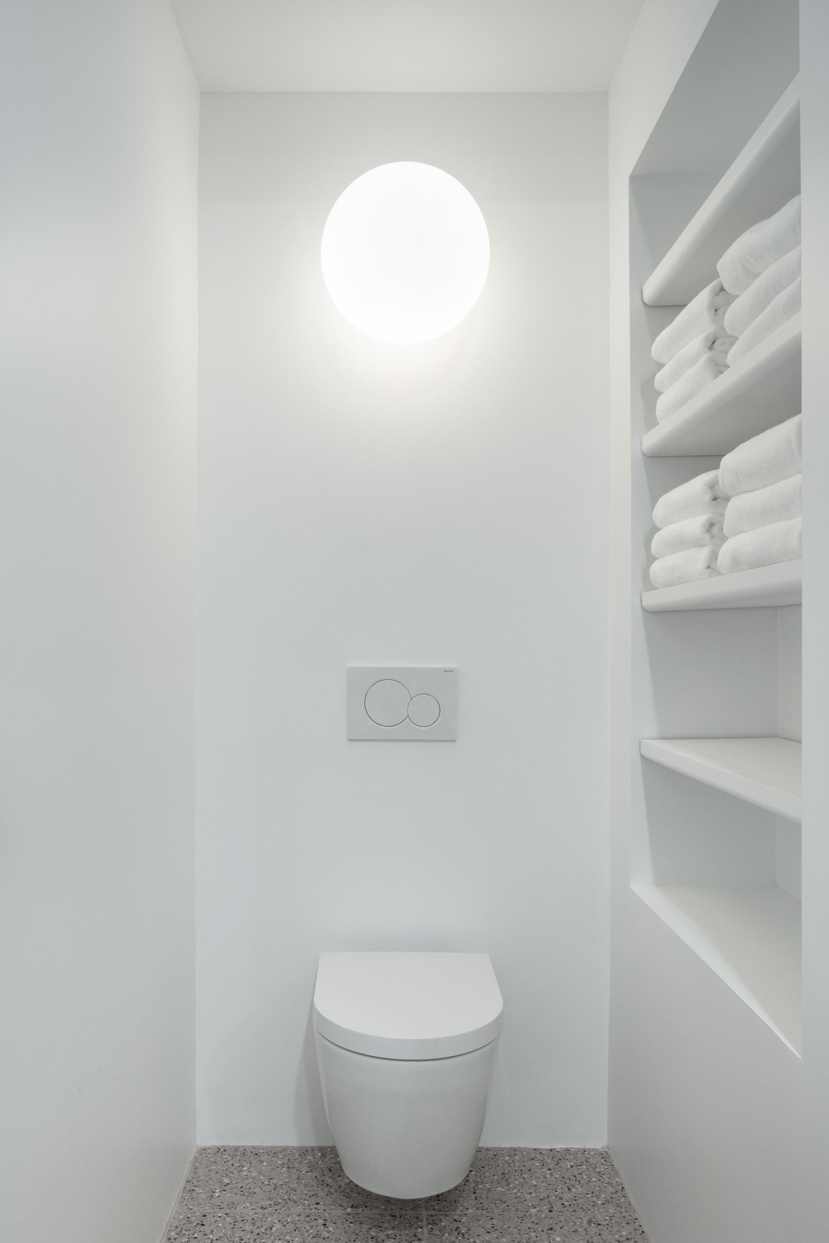A modern white bathroom with a built-in shelving niche.