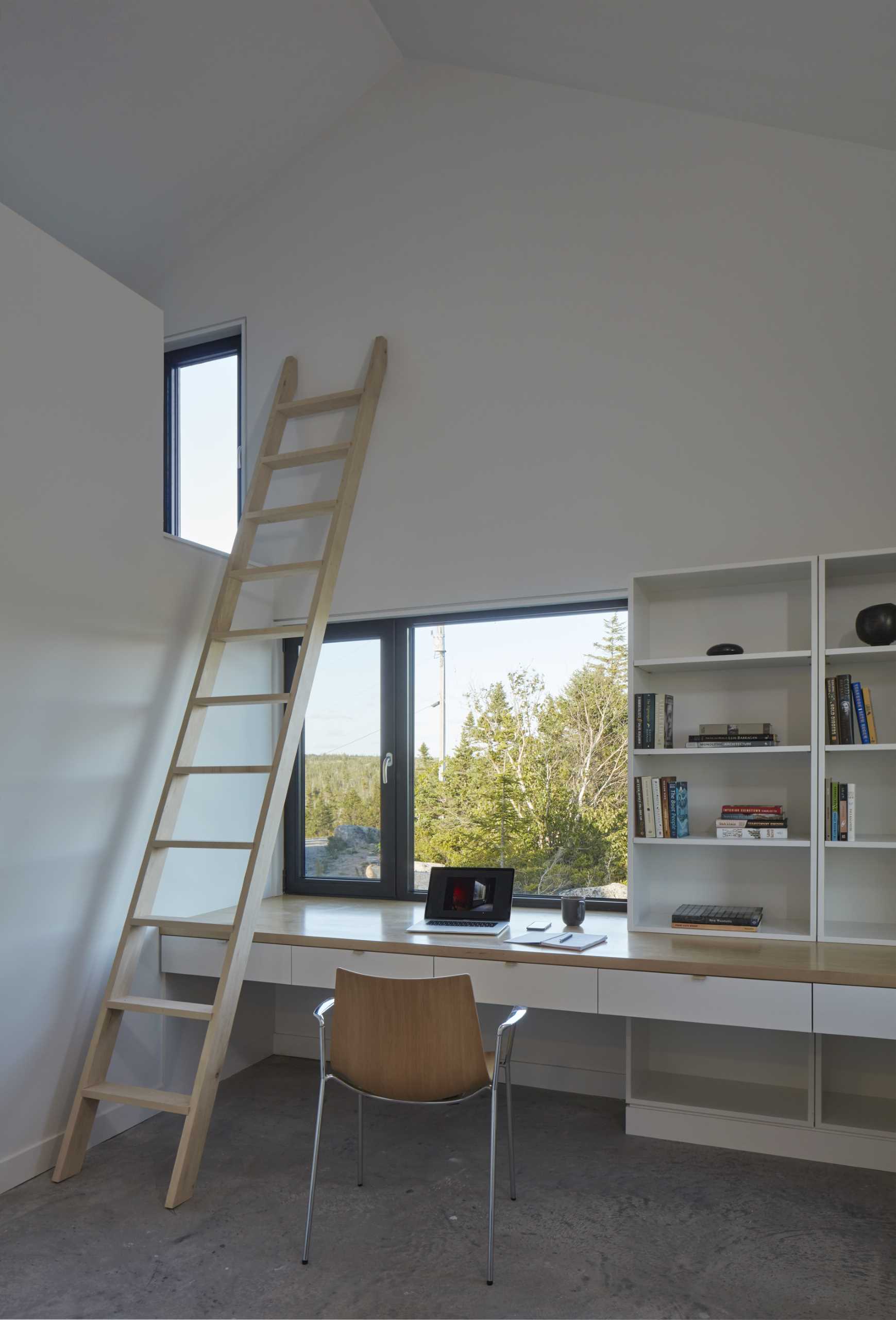 In this modern bedroom, there's a built-in desk and a ladder leading to a loft.