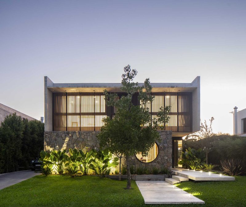 A Round Window Is Nestled Into A Stone Wall On The Front Of This Home