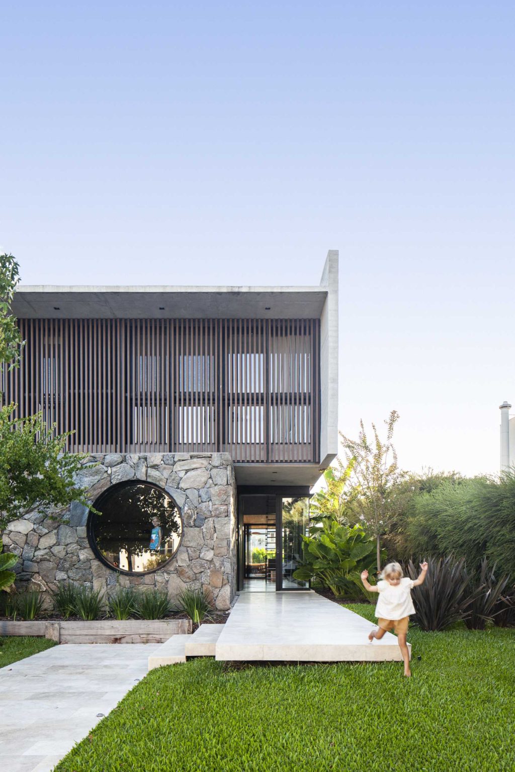 A Round Window Is Nestled Into A Stone Wall On The Front Of This Home