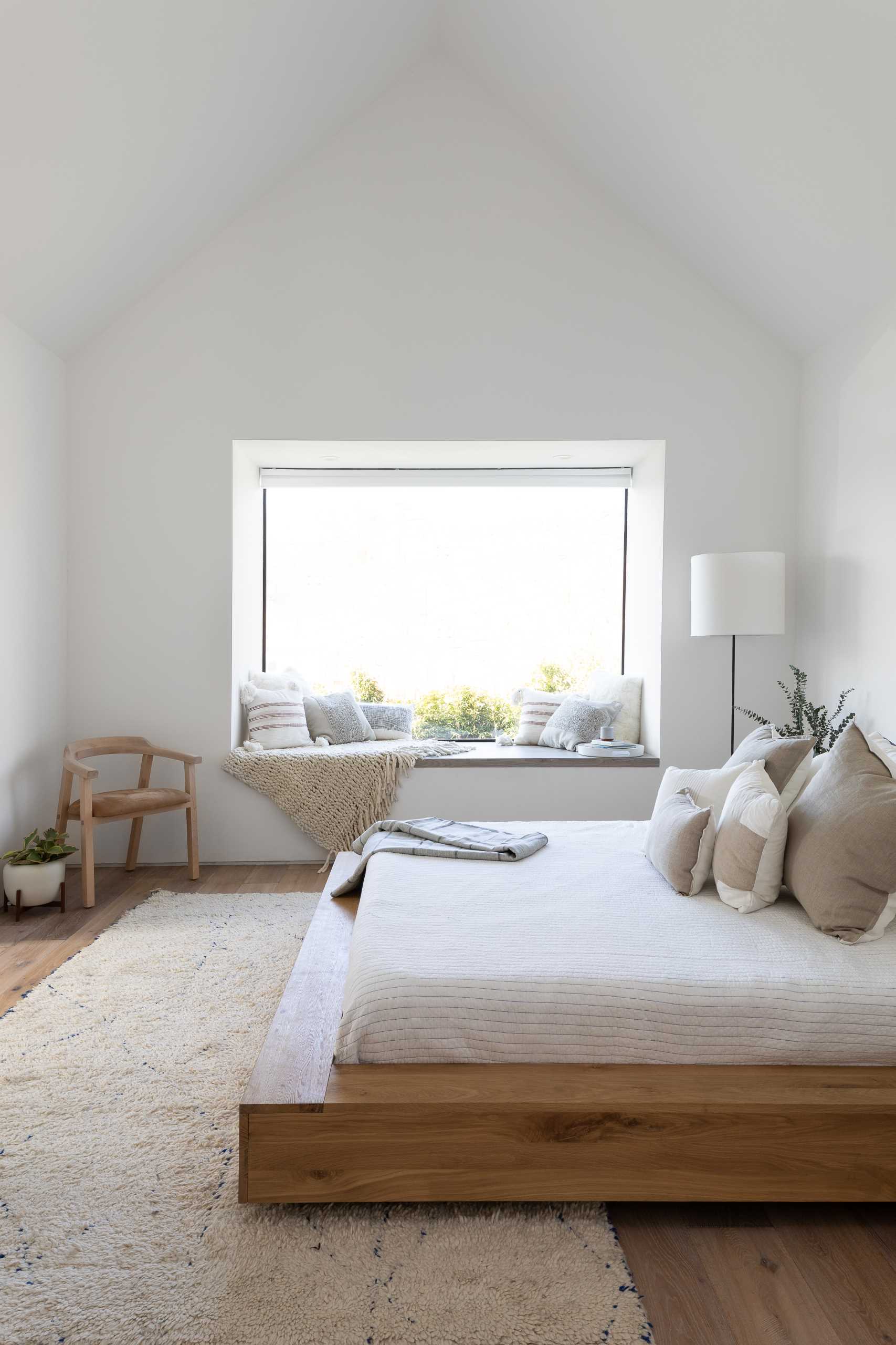 In this modern primary bedroom, the vaulted ceiling makes the room feel large, while a window seat creates a cozy place to relax.