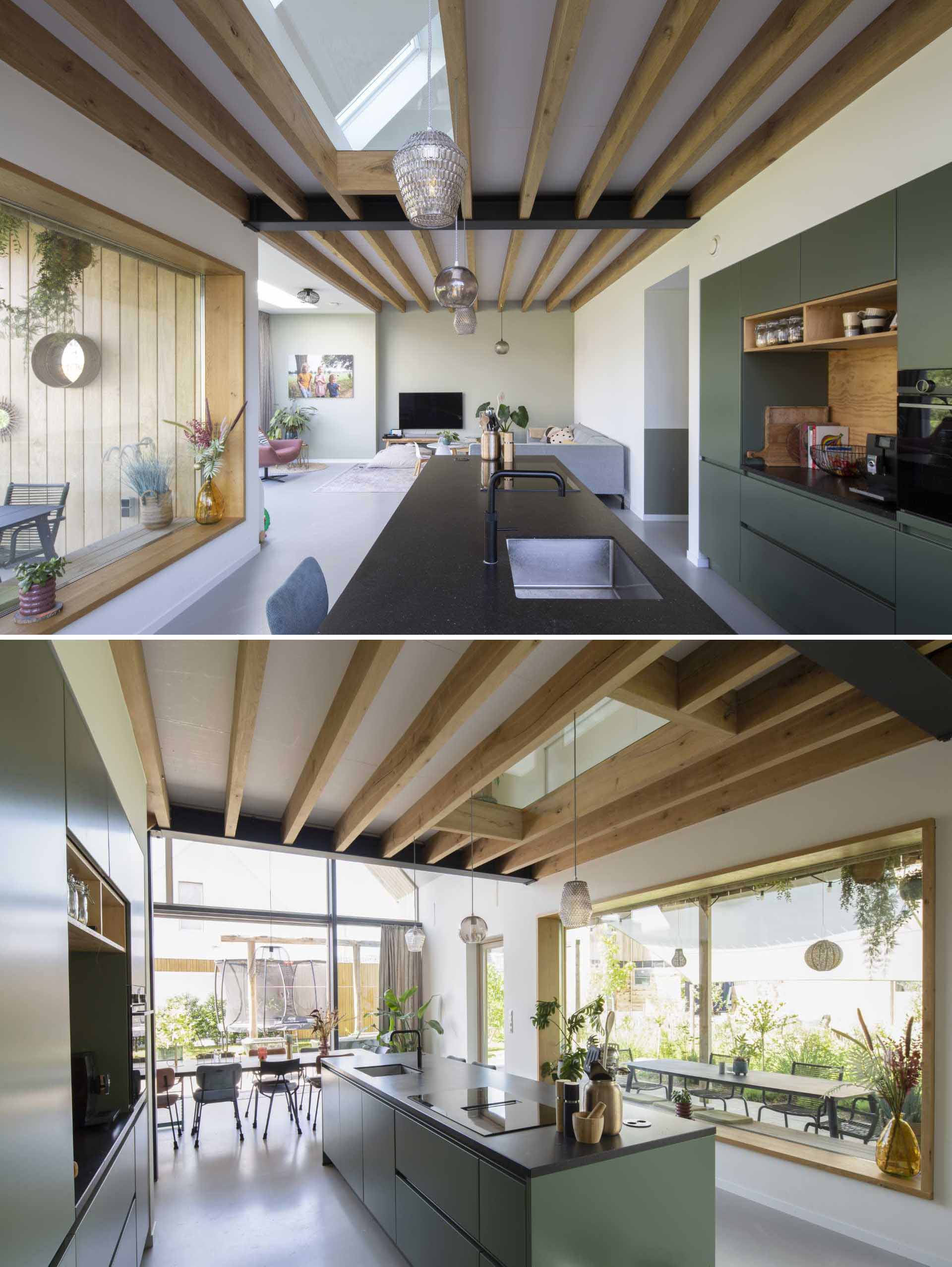 A modern kitchen with matte green cabinets, an island, and a deep window sill.