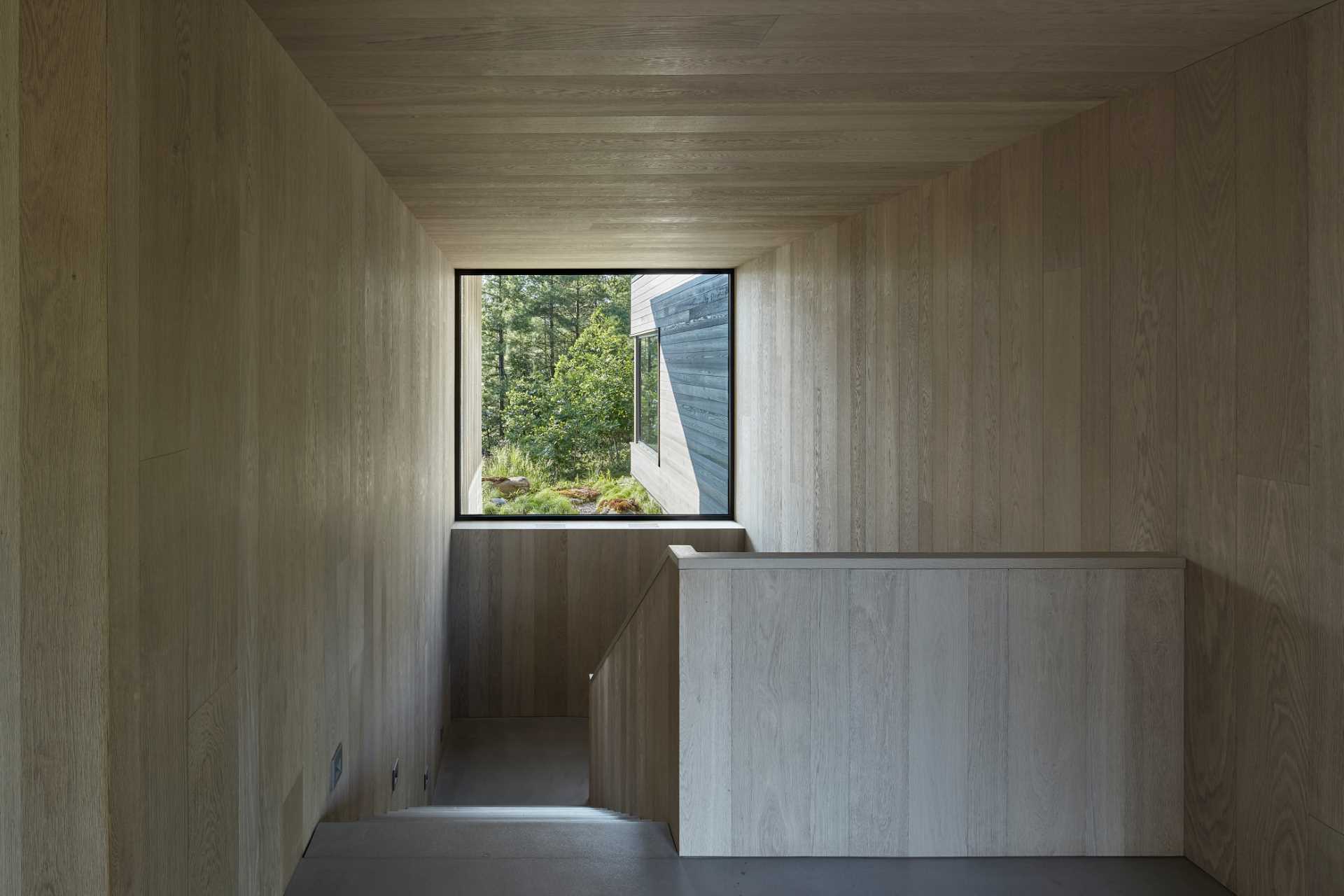 A punch window at the top of the staircase frames the view of the trees and adds natural light to the interior.