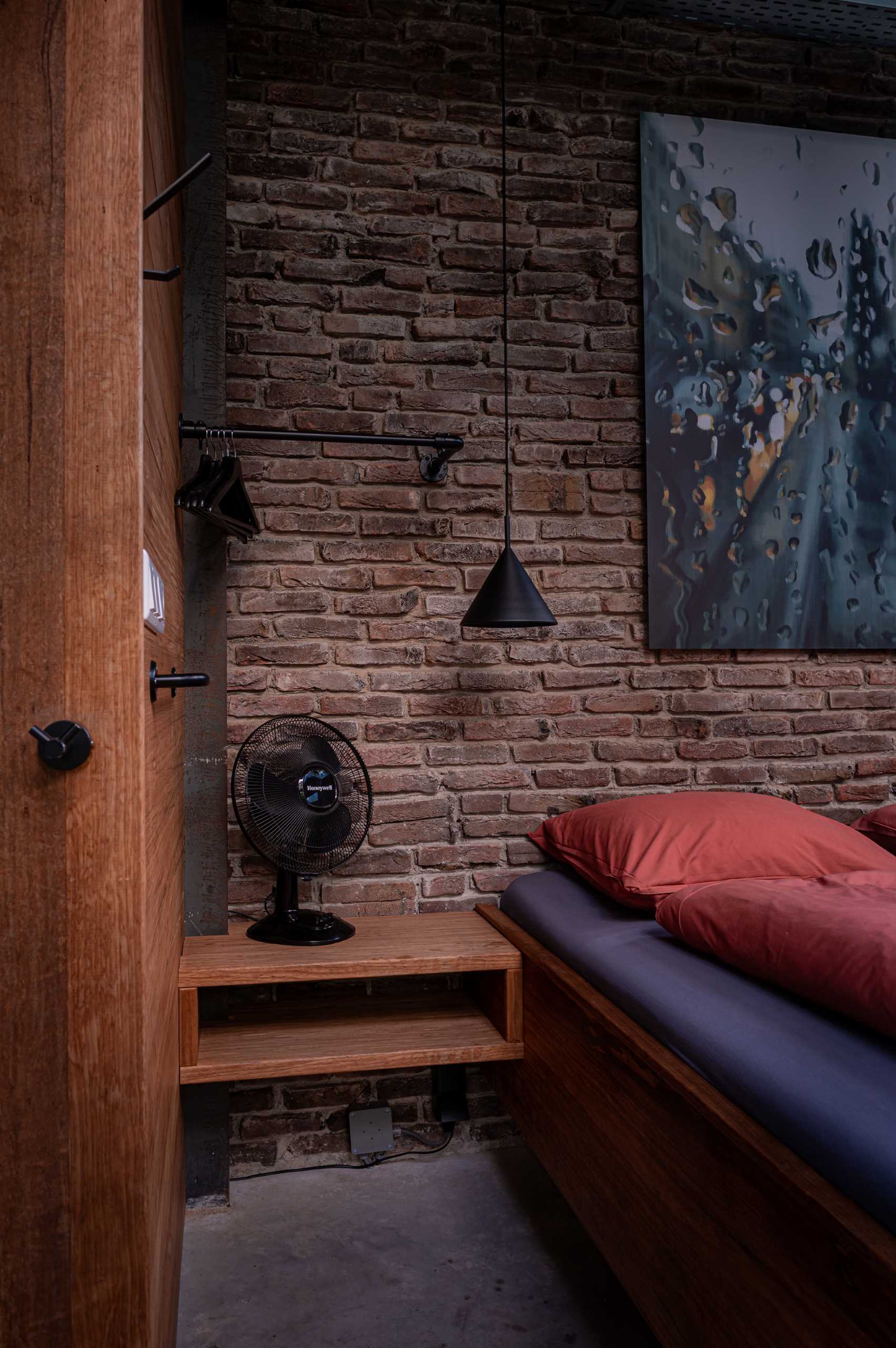 This bedroom with a brick wall has an open bathroom.