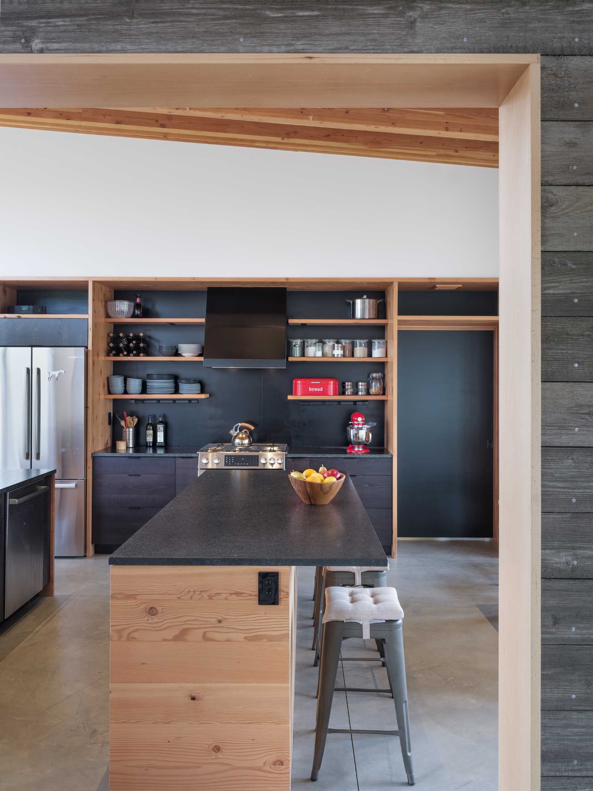 In this kitchen, dark, leathered granite countertops give a crispness to salvaged wood cabinets, which are cleverly positioned to create a room divider and storage.