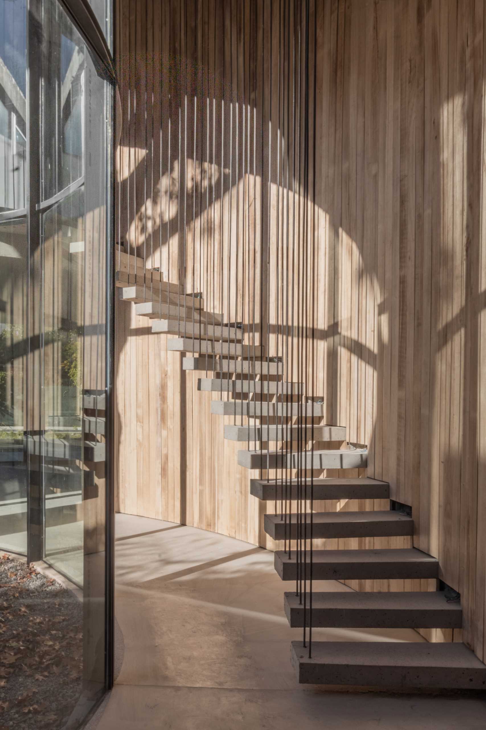 The wall of curving windows fills the space with an abundance of natural light, while the stairs double as a sculptural element that follows the curve.