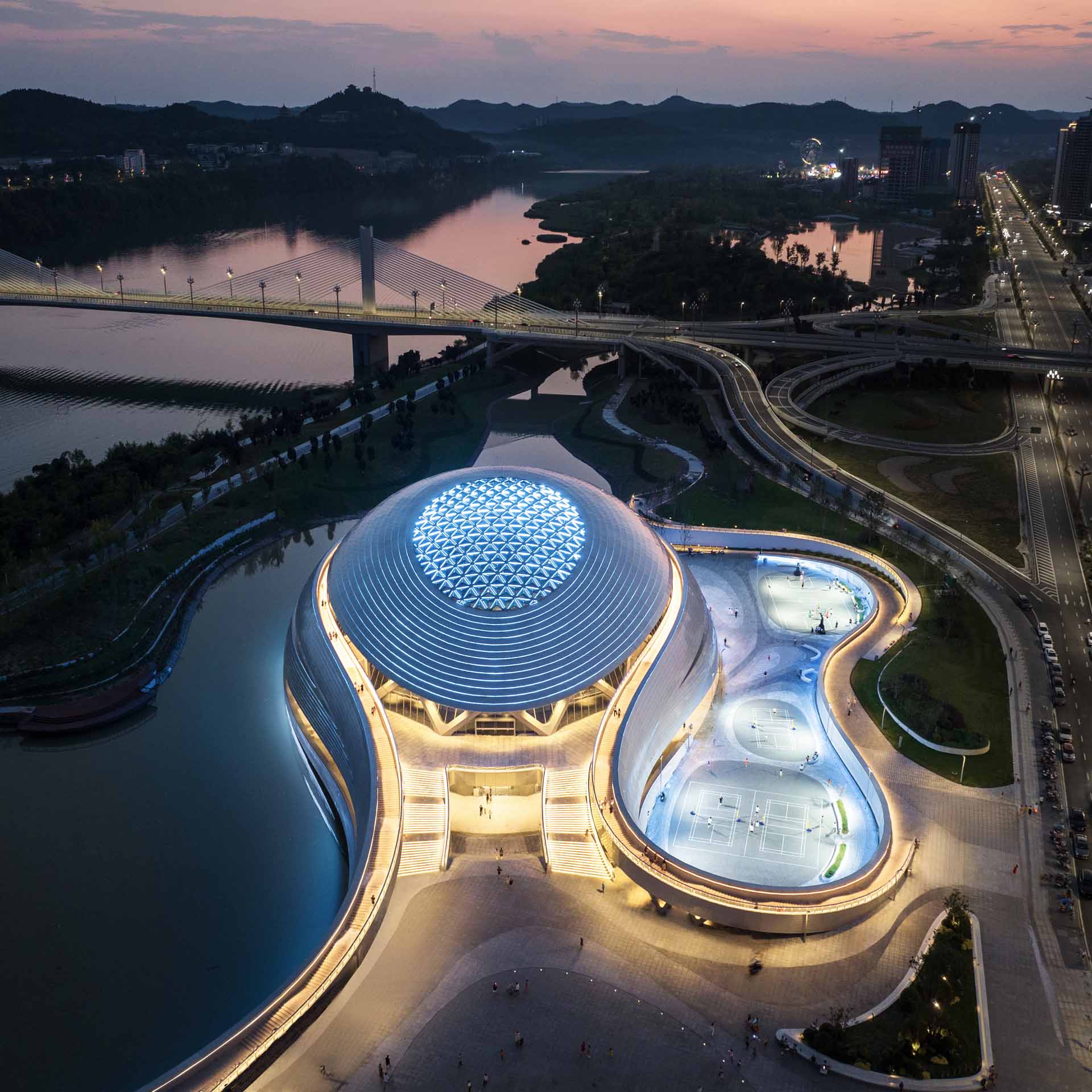 Located by the Jialing River, this gymnasium achieves harmony, openness, and interaction with nature. The overall project is conceived as an earthscape, just like a picture scroll, while city and nature are merged, with the architecture and landscape combined creating a continuous spatial sequence formed along the waterfront.