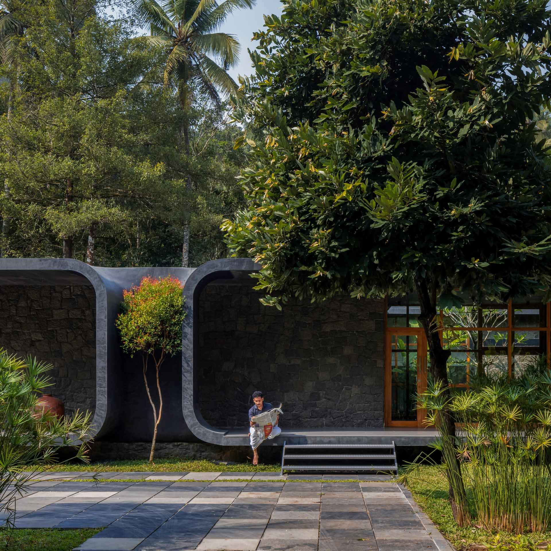 The site's lush surroundings and dense vegetation inspired the design of this home, which has two C shapes that mirror each other, with a tree acting as the focal point.