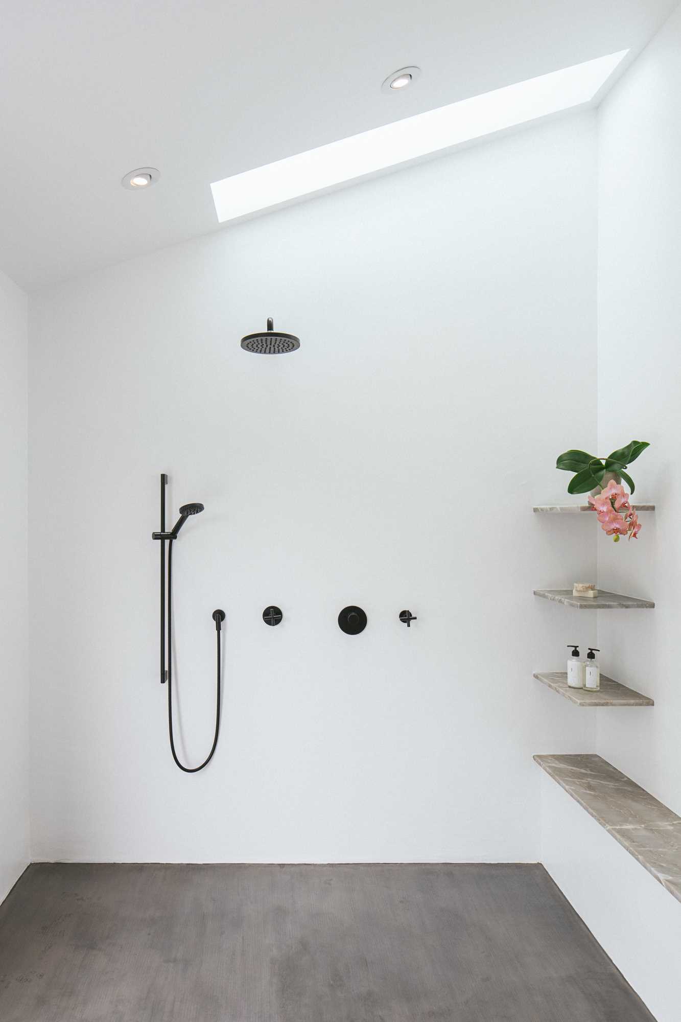 A modern open shower with a skylight and shelving.