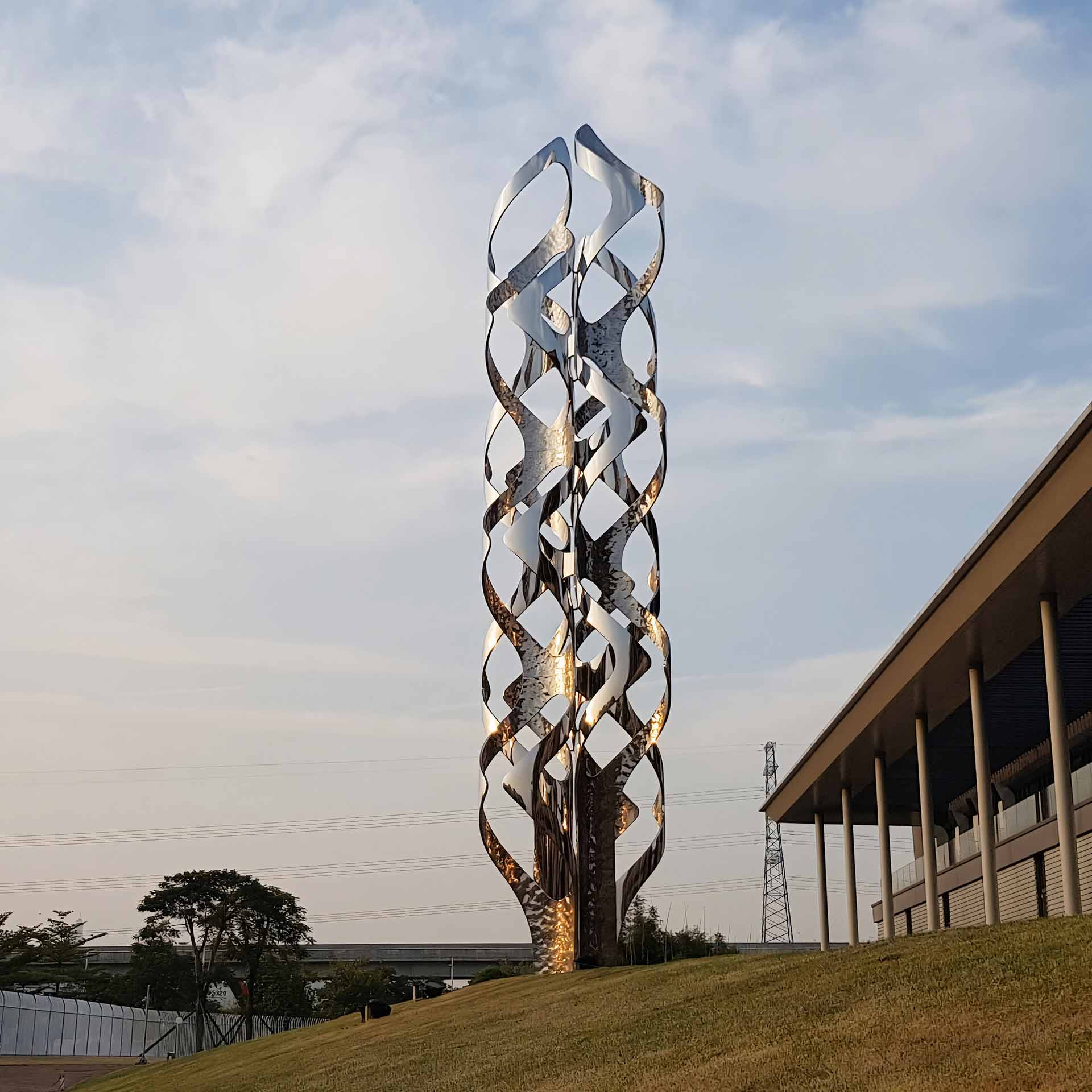 The 10-meter-tall stainless steel sculpture serves as a powerful symbol of a precision metal processing company's core values and vision, while also contributing to the aesthetic appeal of the green square.