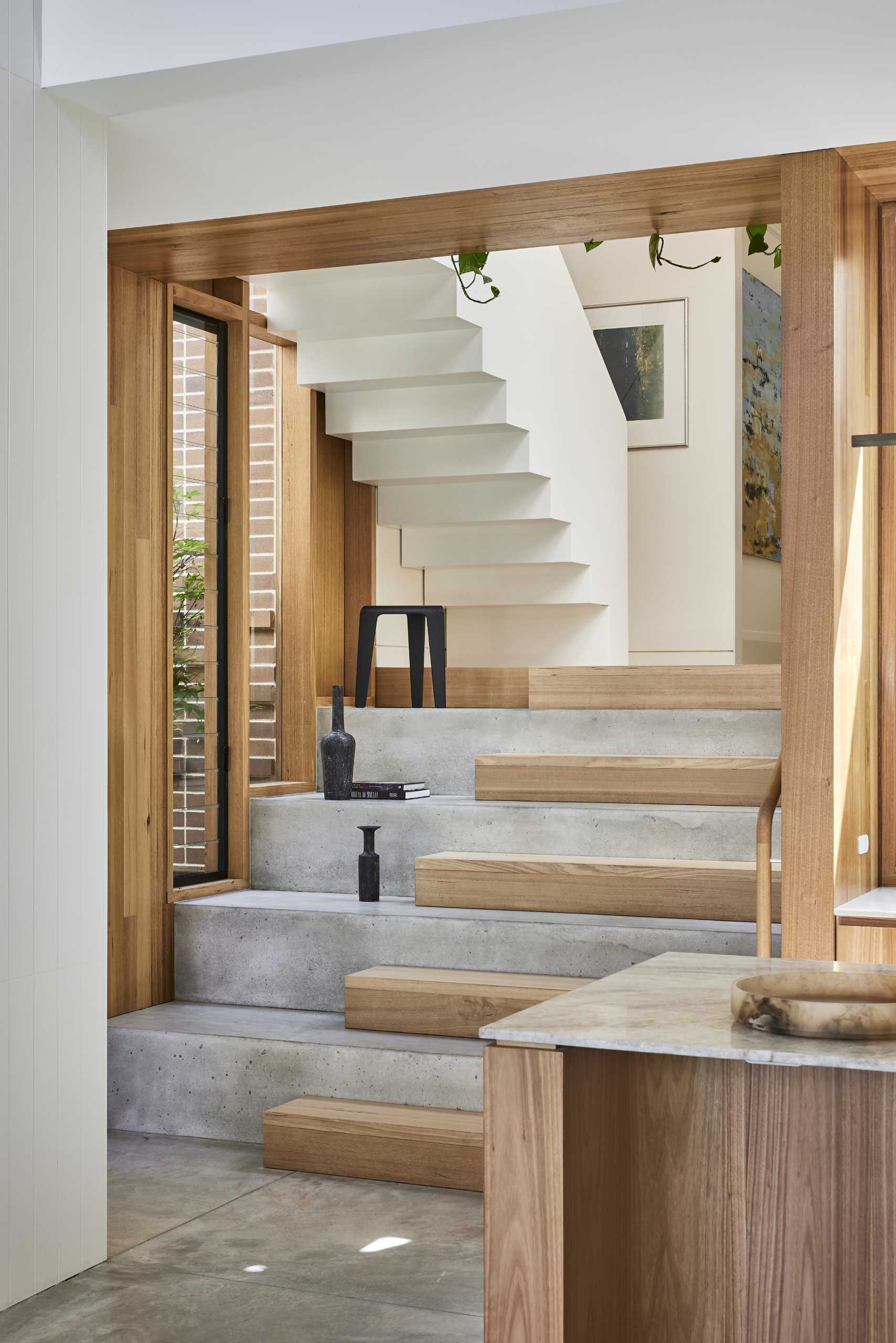 Wood and concrete stairs with white-painted steel handrails connect the new extension with the original home and the upper floor.