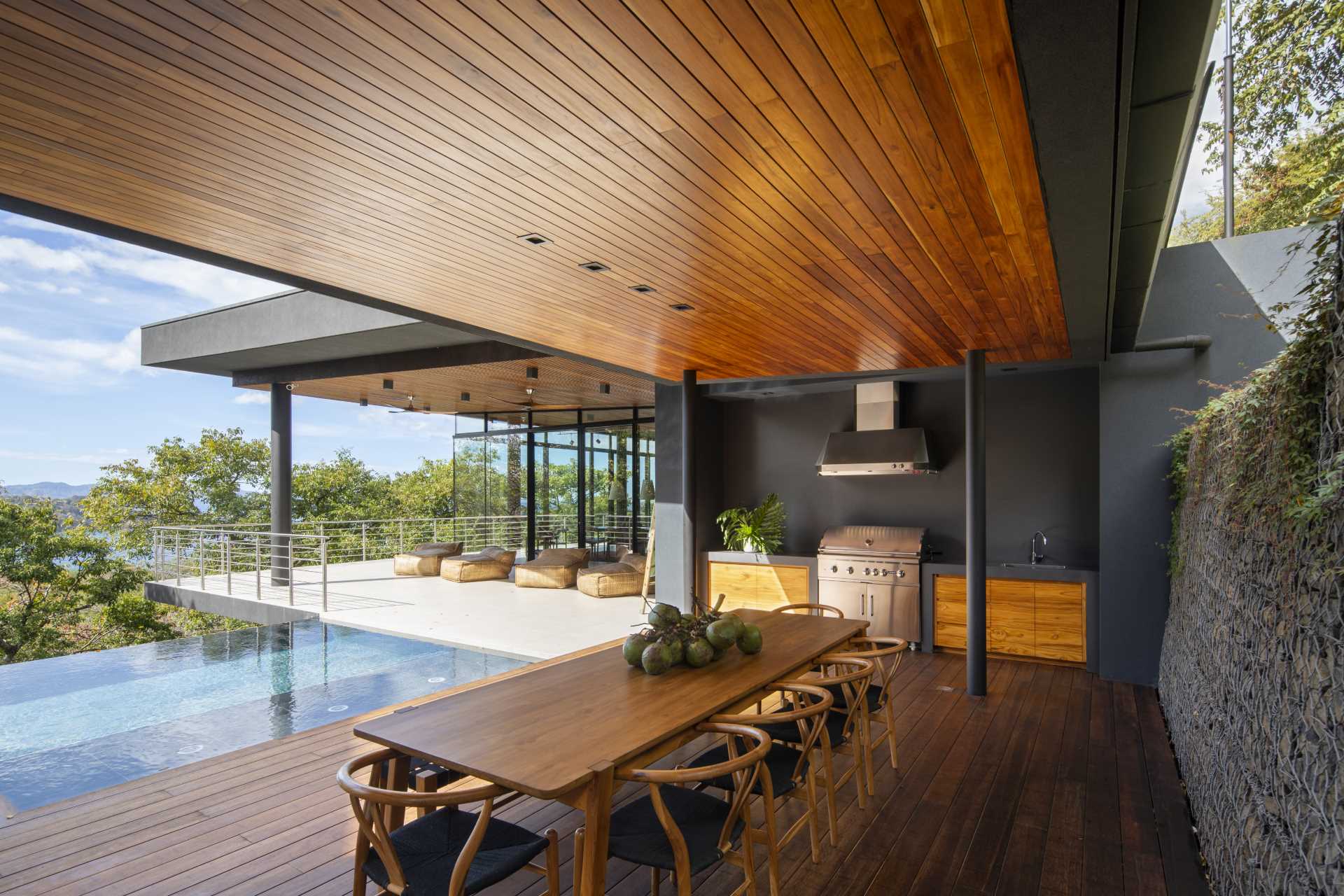 A modern home has covered area by the pool for outdoor dining and an outdoor kitchen.