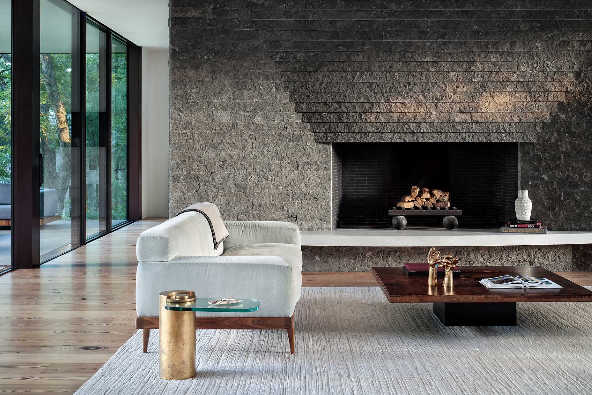 The living room is anchored by a sculptural charcoal limestone fireplace, while a tray ceiling unifies and accentuates the living and dining areas. The floors are surfaced with wide planks of reclaimed long-leaf pine.