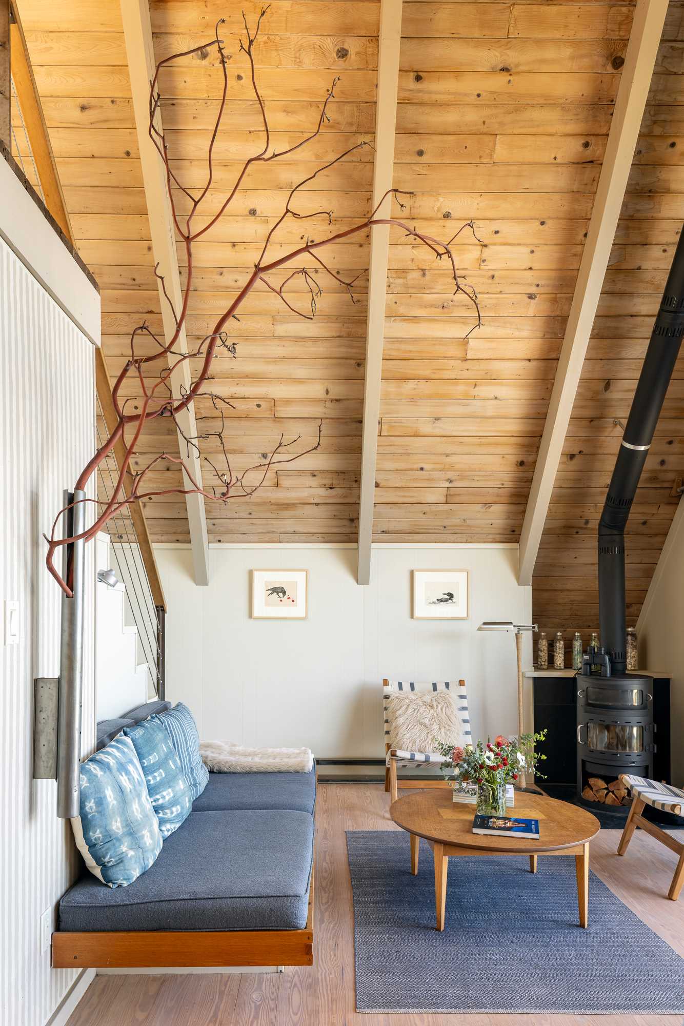 In this renovated A-frame home, reclaimed pine has been used for the flooring and the original exposed fir structure is finished with wood bleach, while the beams are painted to cover an original coffee-brown stain.