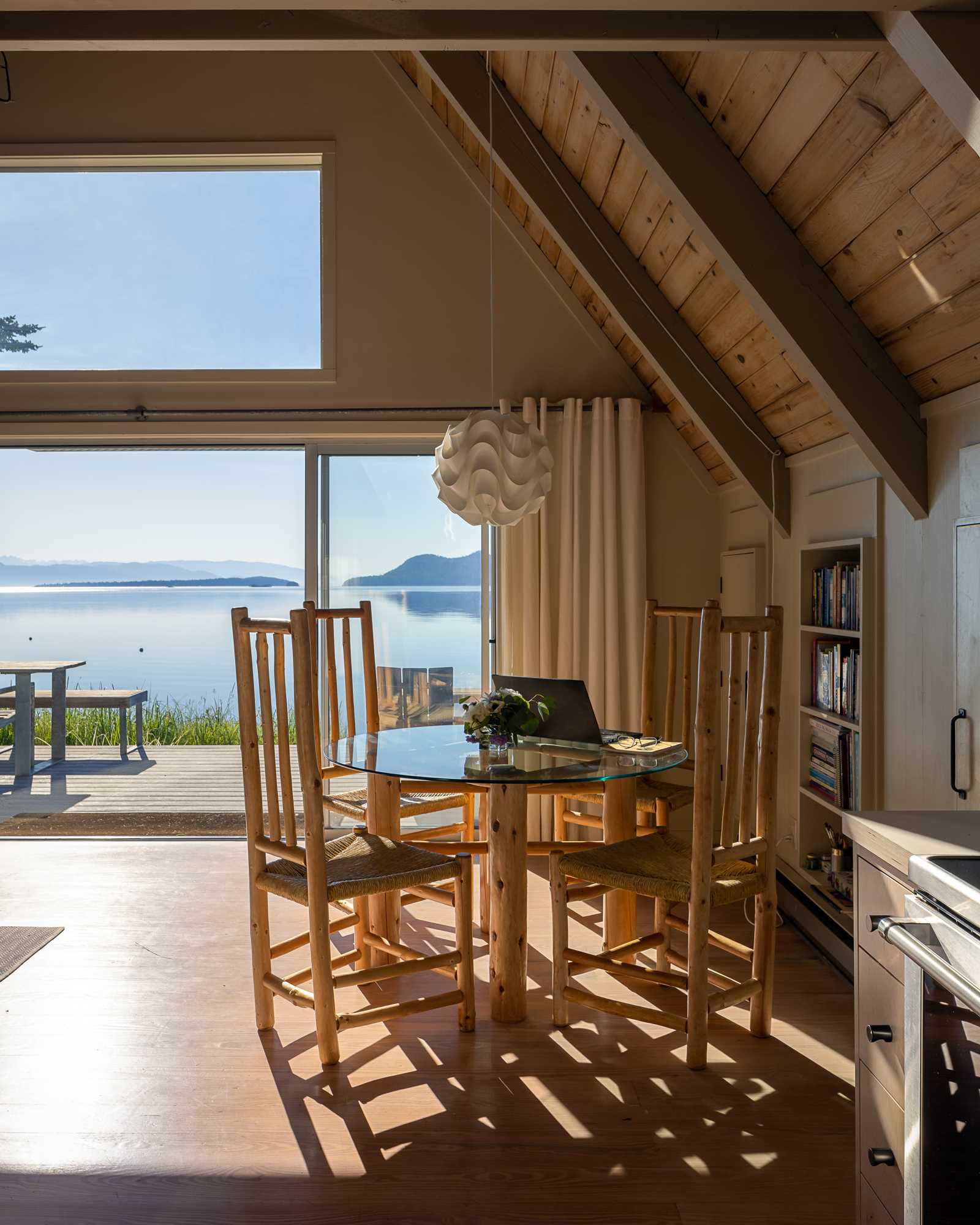 The social areas of this A-frame home connect with the outdoor spaces via sliding doors, which also provide a view of the water.