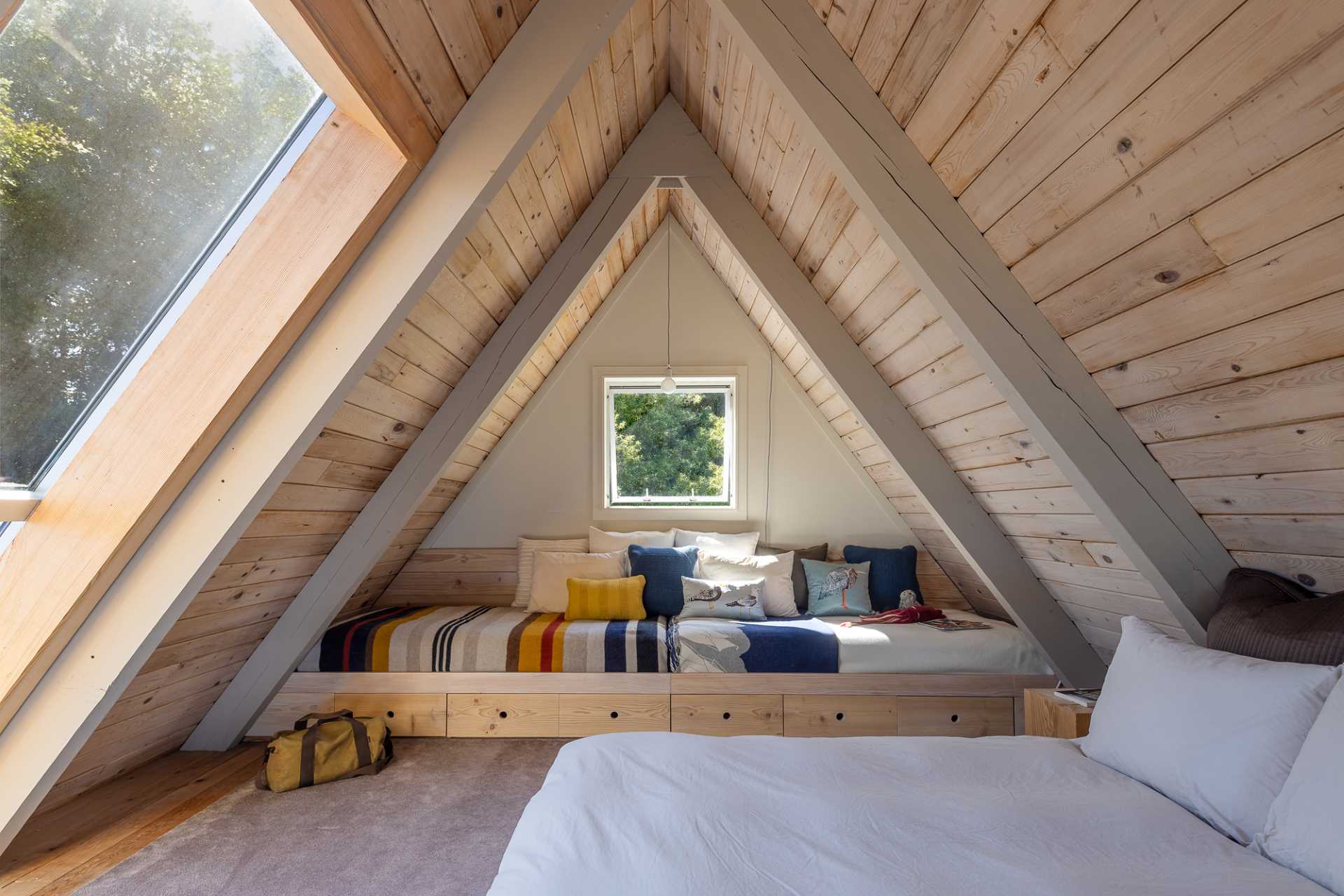 This bedroom in an A-Frame home includes a freestanding bed as well as built-in beds.