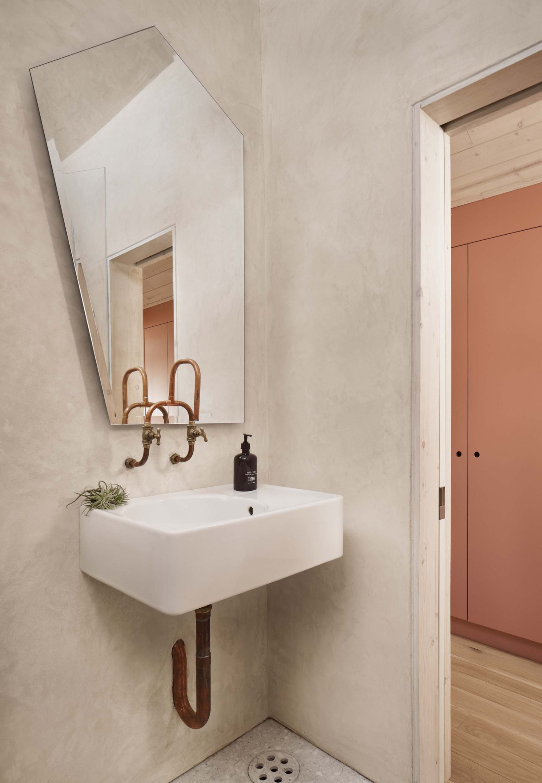 A bathroom includes an angular mirror, a shower with shelving niches, and a skylight.