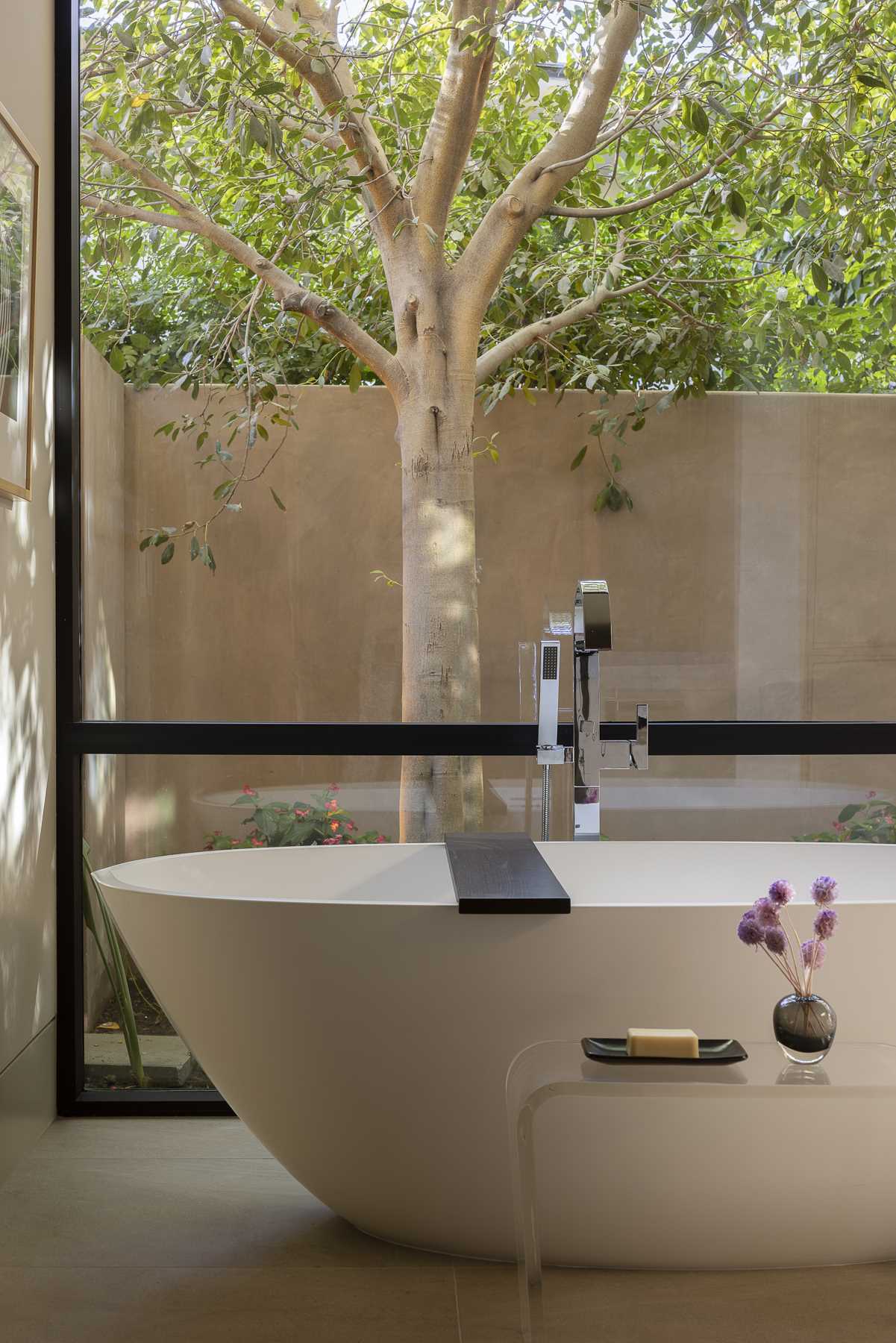 In a bathroom, skylights provide natural light, while the windows frame the tree views from the bath and the s،wer.