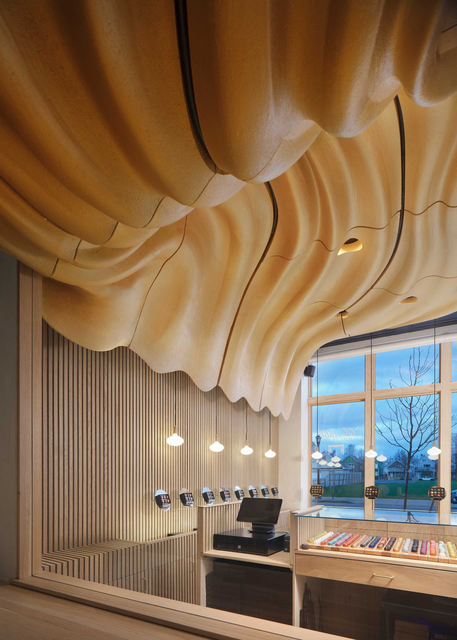 A modern retail chocolate store with a sculptural ceiling that was inspired by flowing untempered chocolate.