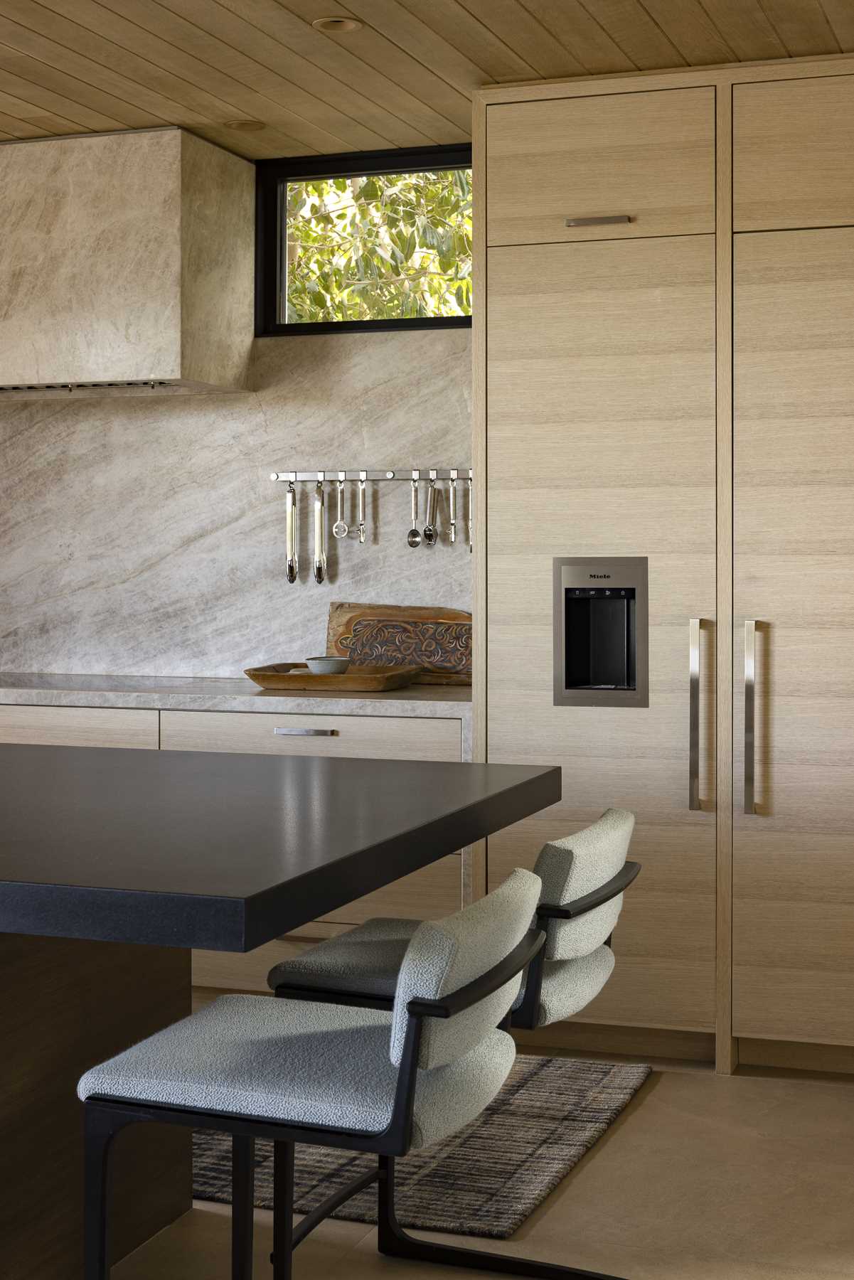 The dining area is adjacent to the kitchen, which includes light wood cabinets and an island with a black countertop.