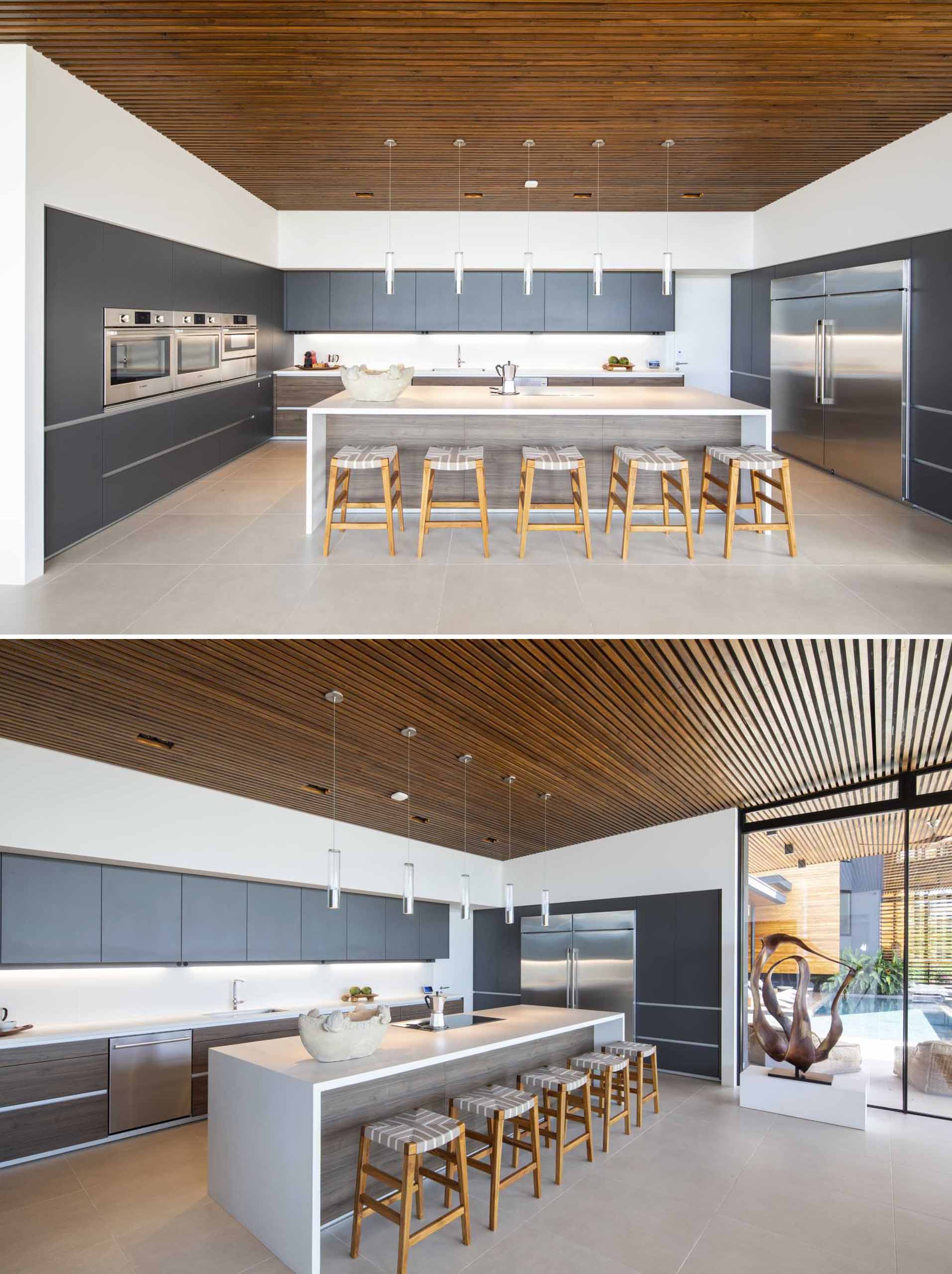 A modern kitchen with grey cabinets, white countertops, and large island.