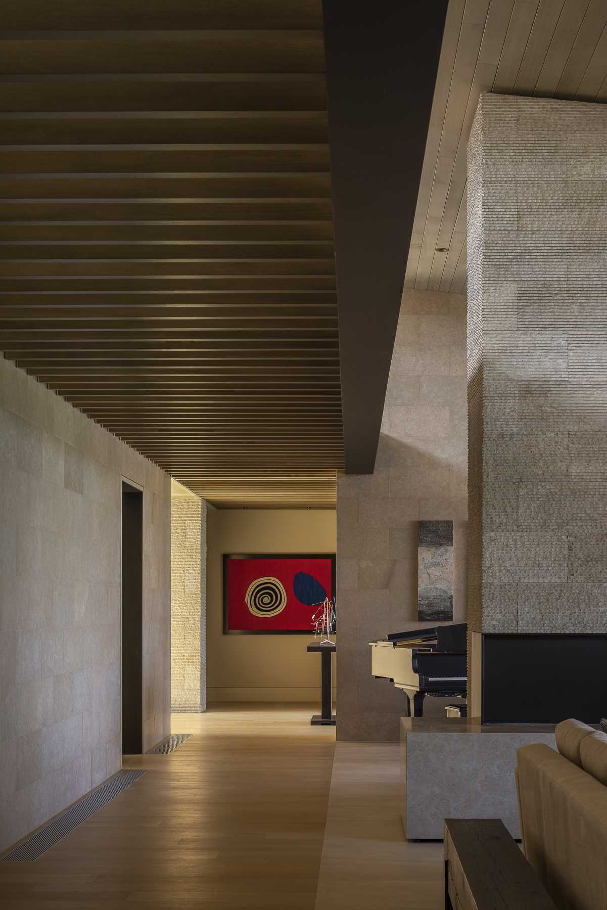 In this modern house, the texture of the limestone varies and defines the different zones within the home, while flooring transitions from tile to wood.