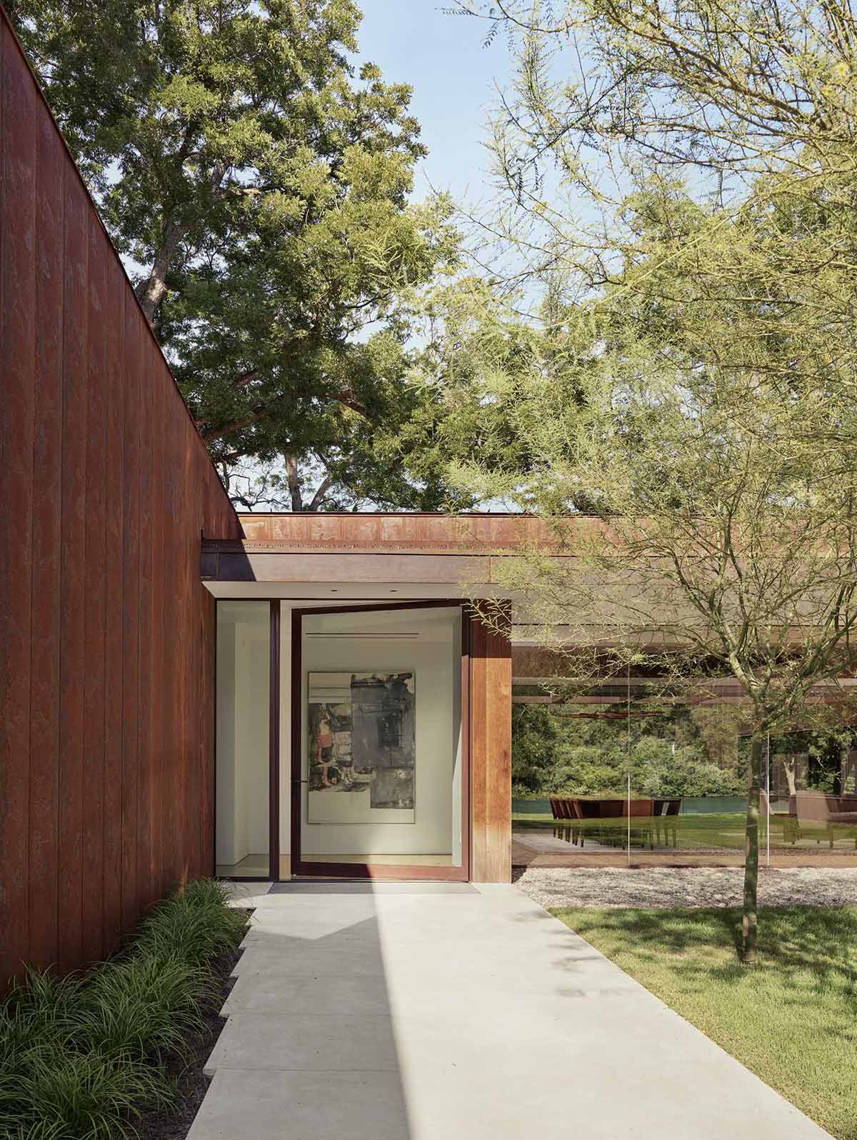 A path lined with Palo Verde trees leads to the entryway with a ten-foot-tall, pivoting glass front door.