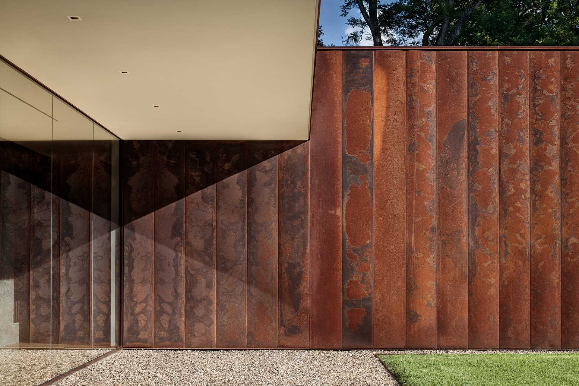 A modern house clad in weathering steel, ash wood accents, and windows, all of which help to create a modern appearance.