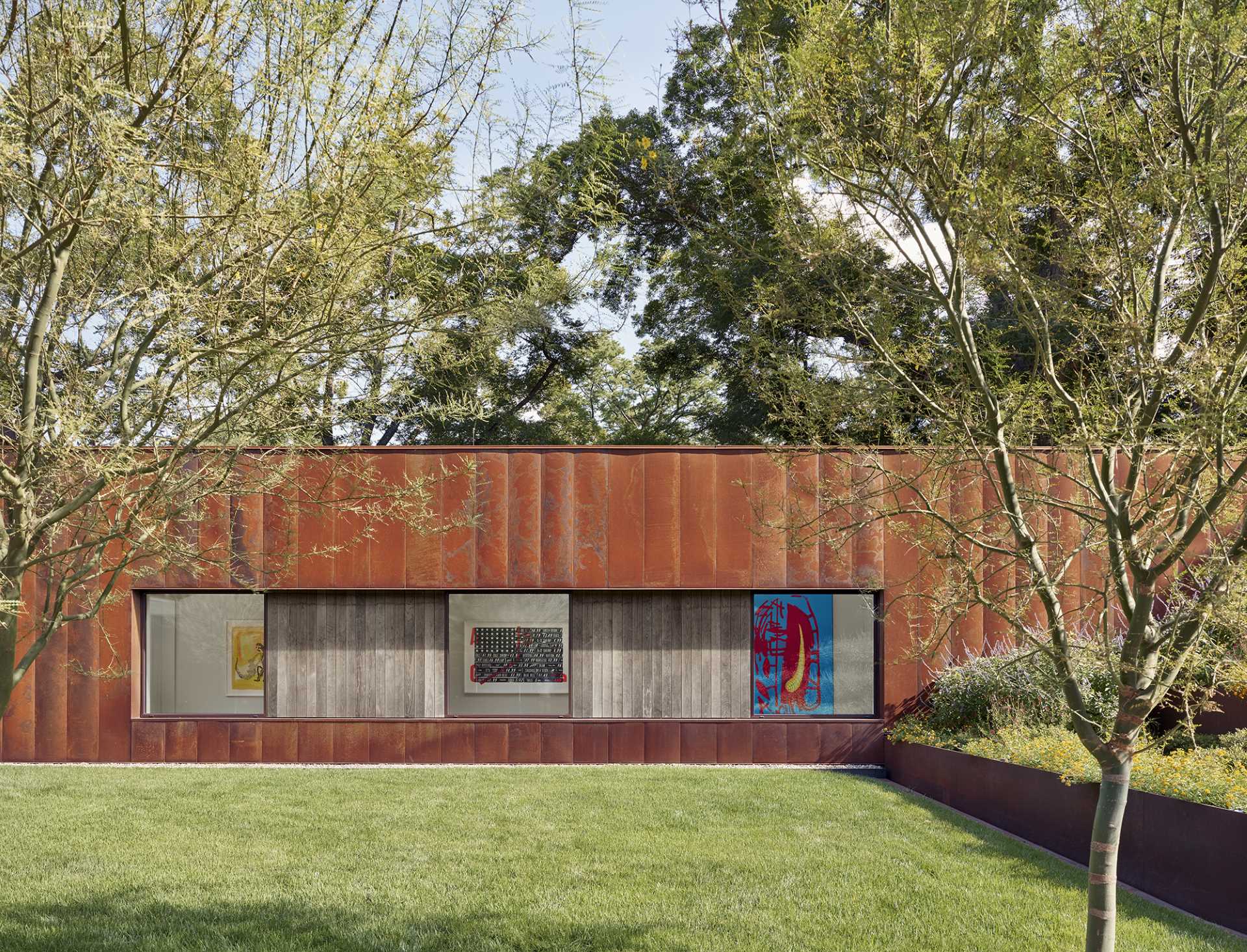 A modern house clad in weathering steel, ash wood accents, and windows, all of which help to create a modern appearance.