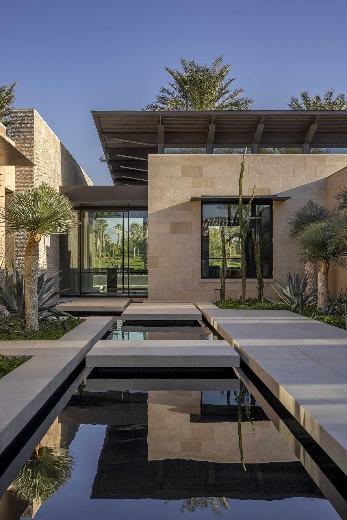 Upon arrival at the home, there's a carefully crafted entry path, navigating stairs and reflective ponds before crossing water via concrete lily pads to reach the entrance.