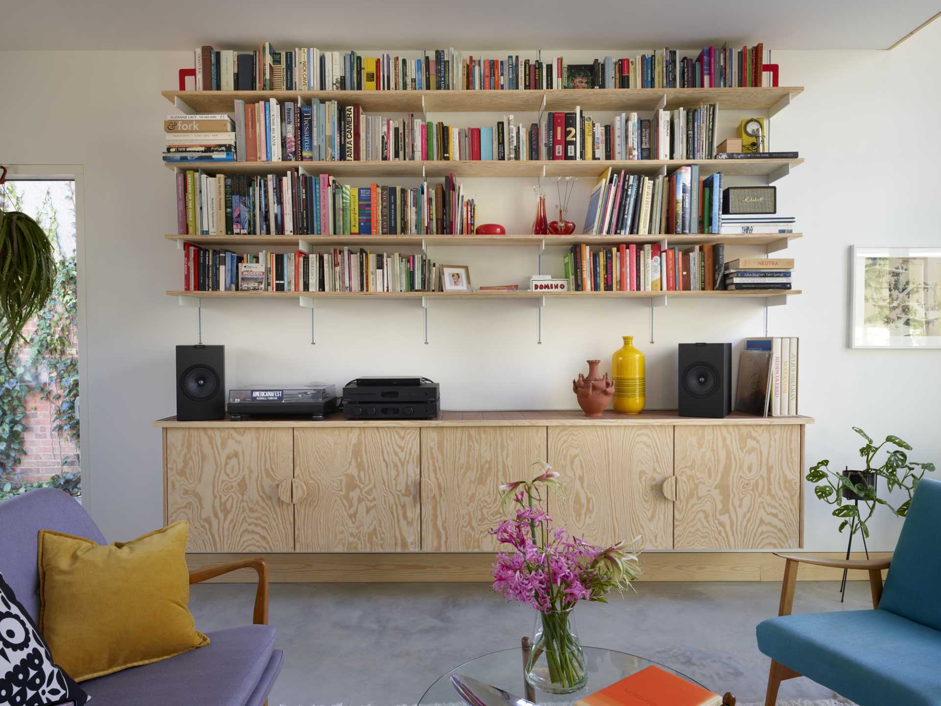 In the living room, a floating wood console provides storage and a place for a record player.
