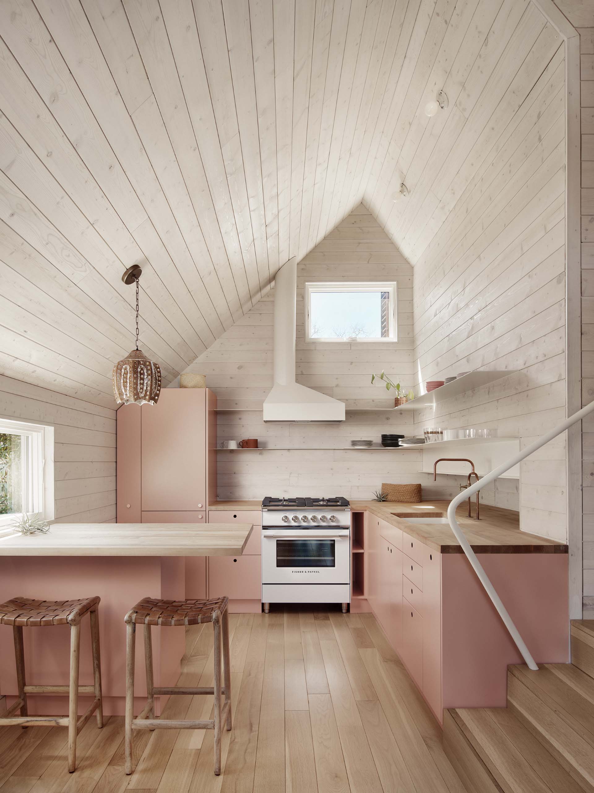 This kitchen features pastel pink cabinets from Ikea have custom-painted fronts, and are topped with off-t،lf Boos butcher block countertops.