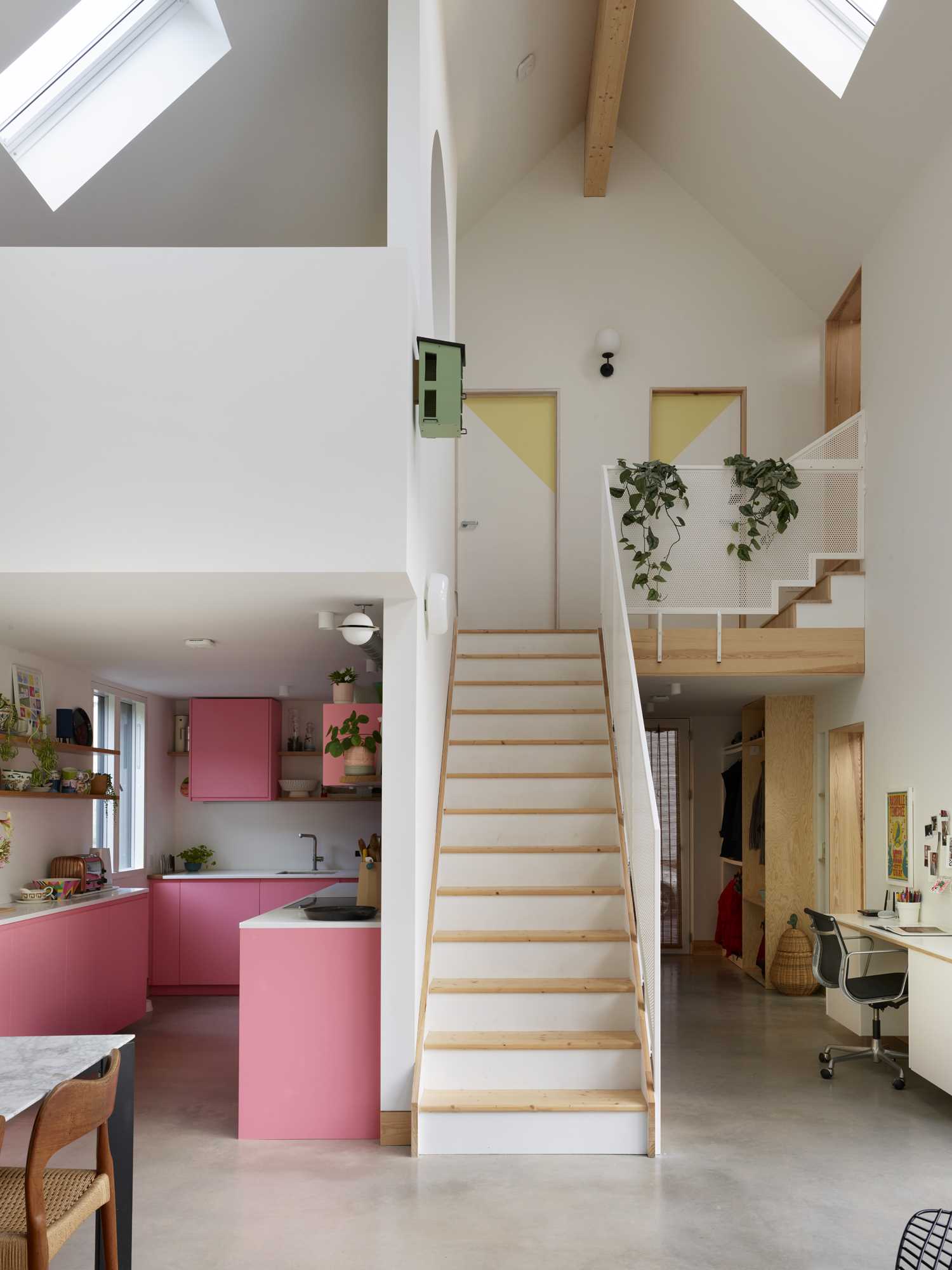 An unexpected design detail in this contemporary home is the kitchen with its pink cabinets, which are complemented by white countertops and floating wood shelves.