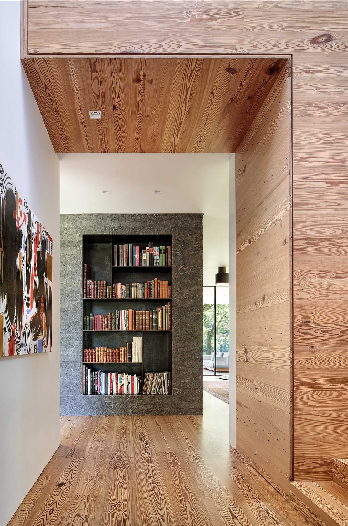 Steel bookshelves are nestled into both sides of the limestone fireplace surround, while wood stairs connect to the bedrooms and bathrooms.