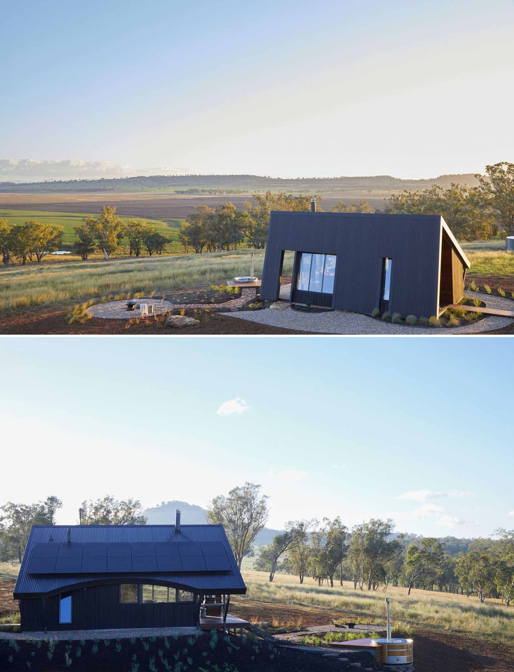 A small off-grid modern cabin that has a wrapping metal roof to protect it from the elements.
