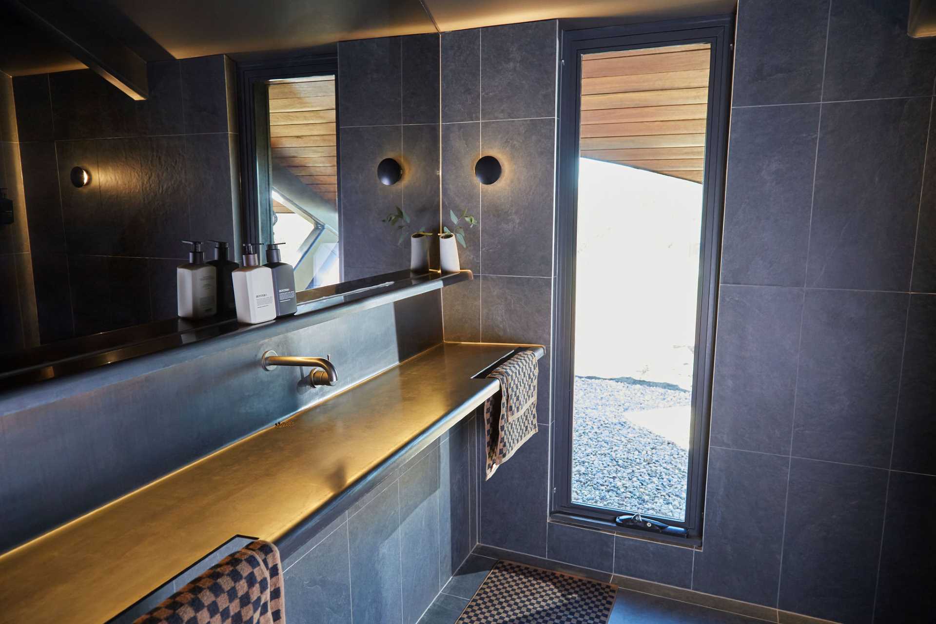 The small bathroom of this modern cabin includes all of the necessities and a vertical window for natural light.
