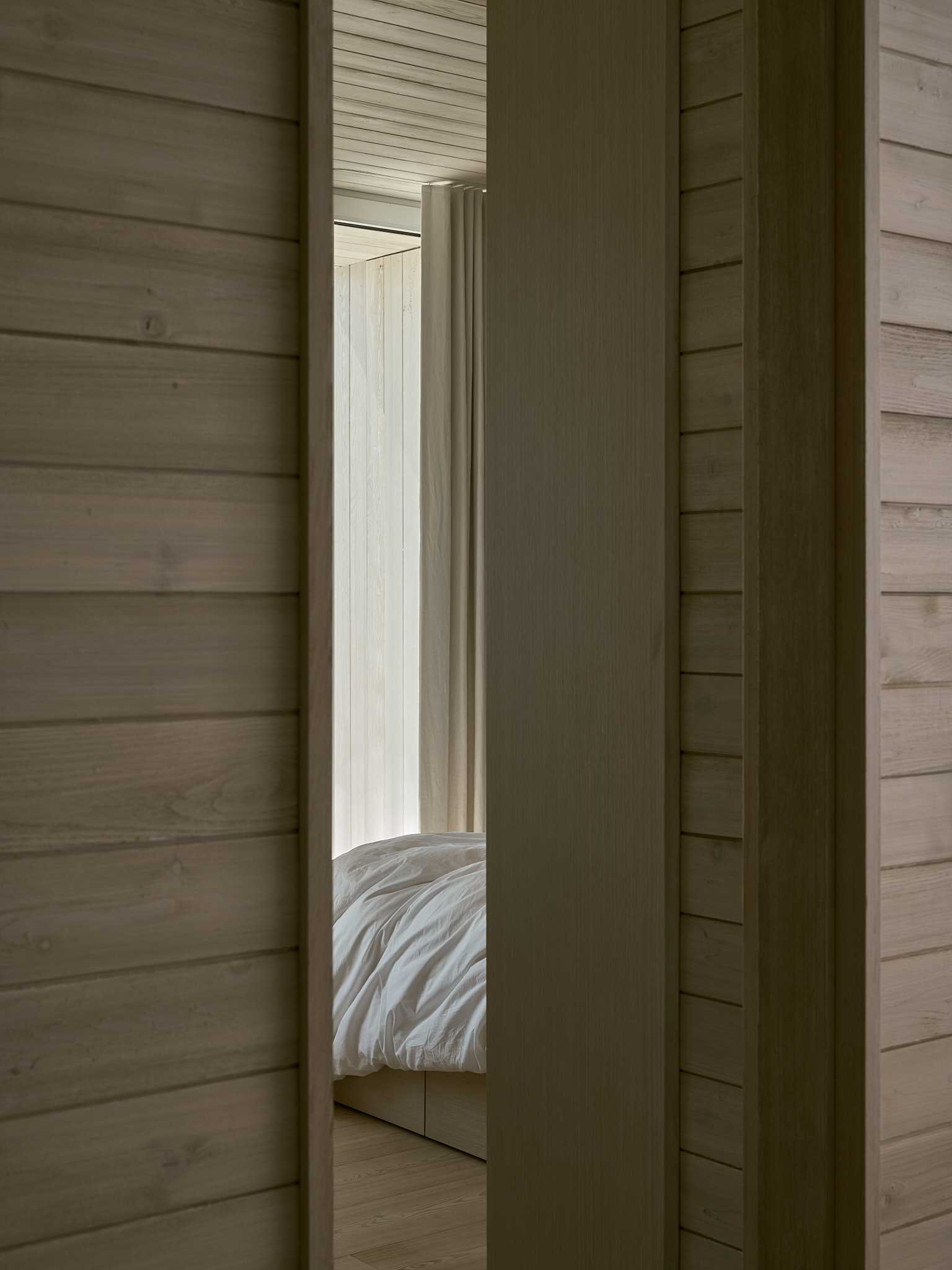 A contemporary bedroom with a wood bed frame and white bedding.